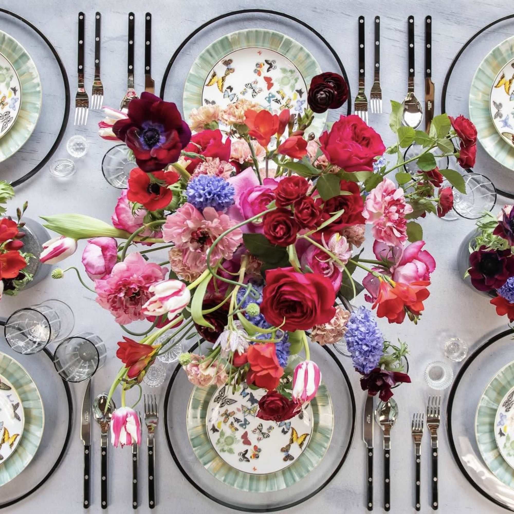 Colorful floral centerpiece on a set table with butterfly plates