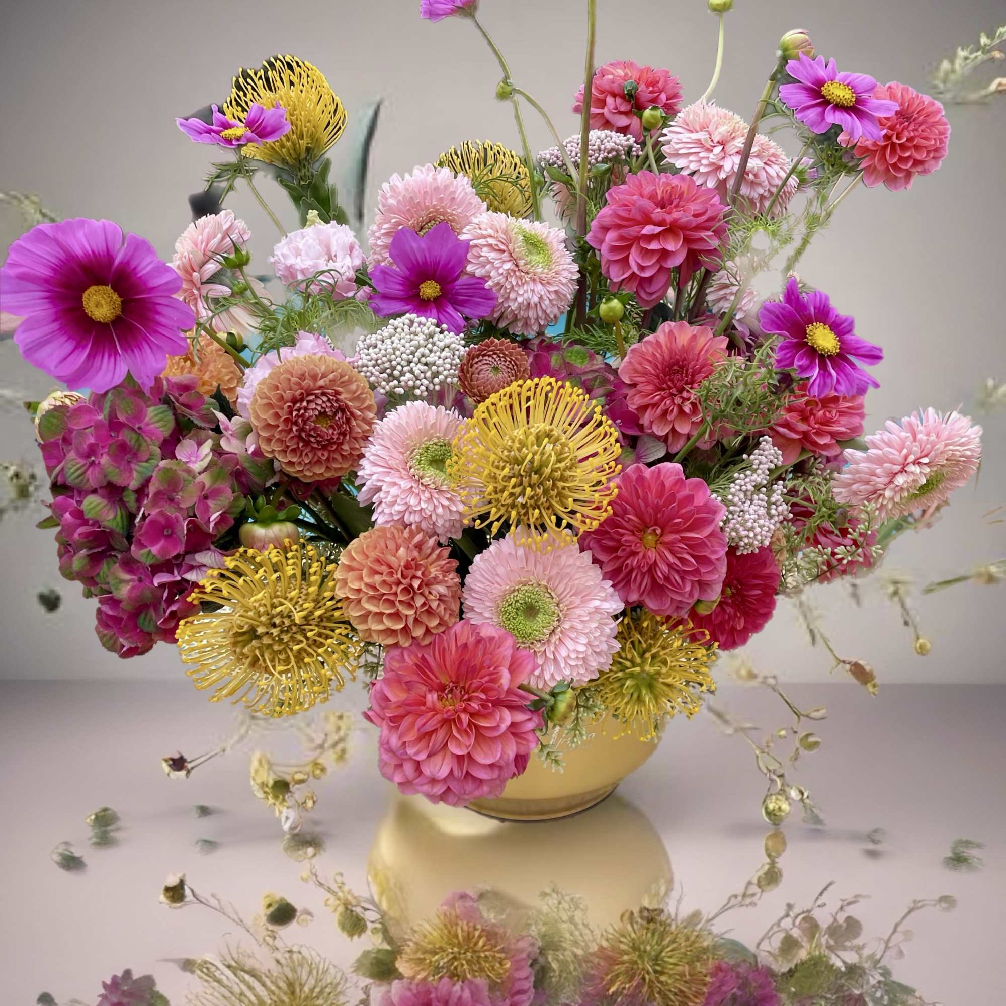 Mixed pink and yellow flower arrangement in a round vase
