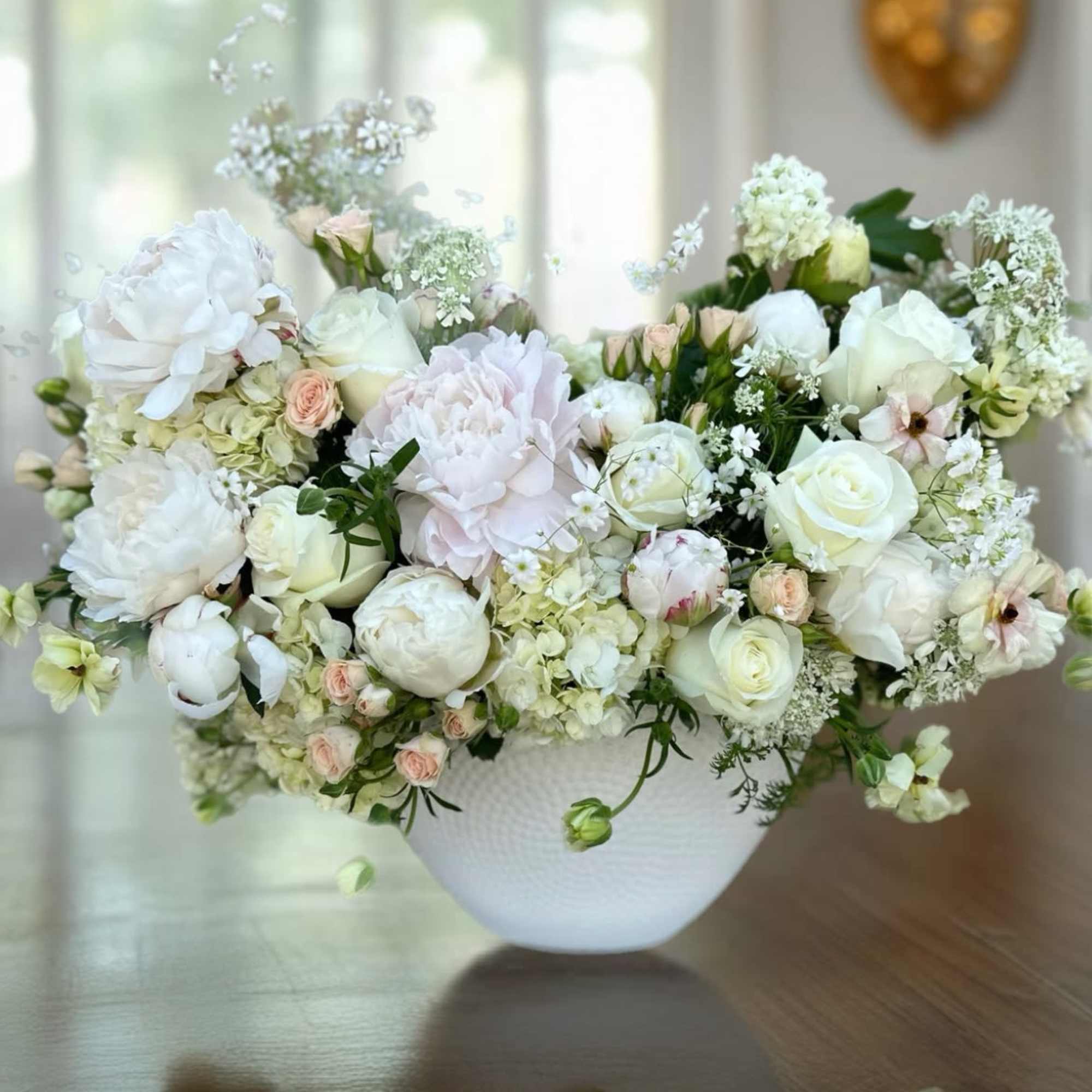 White and blush floral arrangement in a white bowl vase