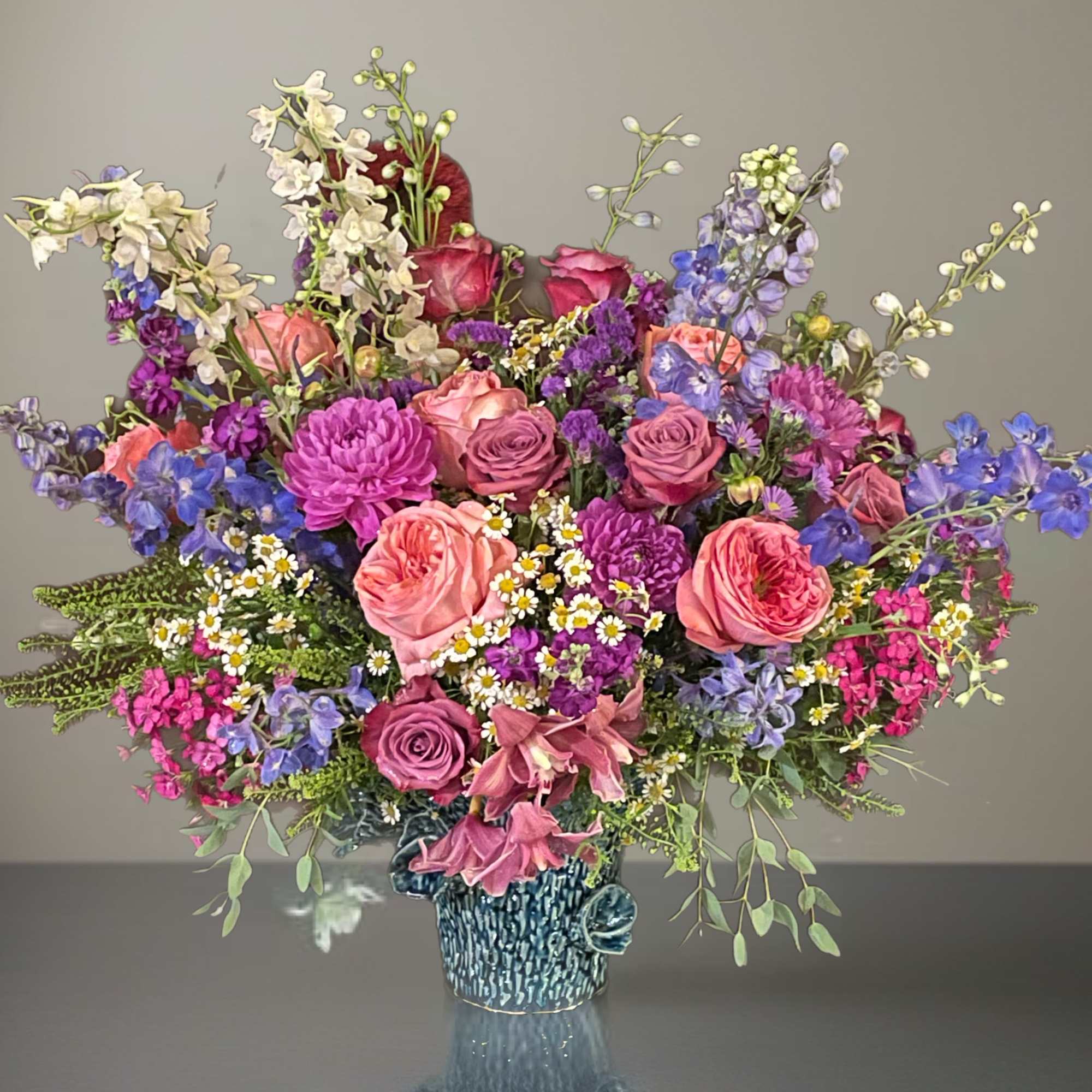 Colorful mixed bouquet in a blue vase with pink, purple, and white blooms