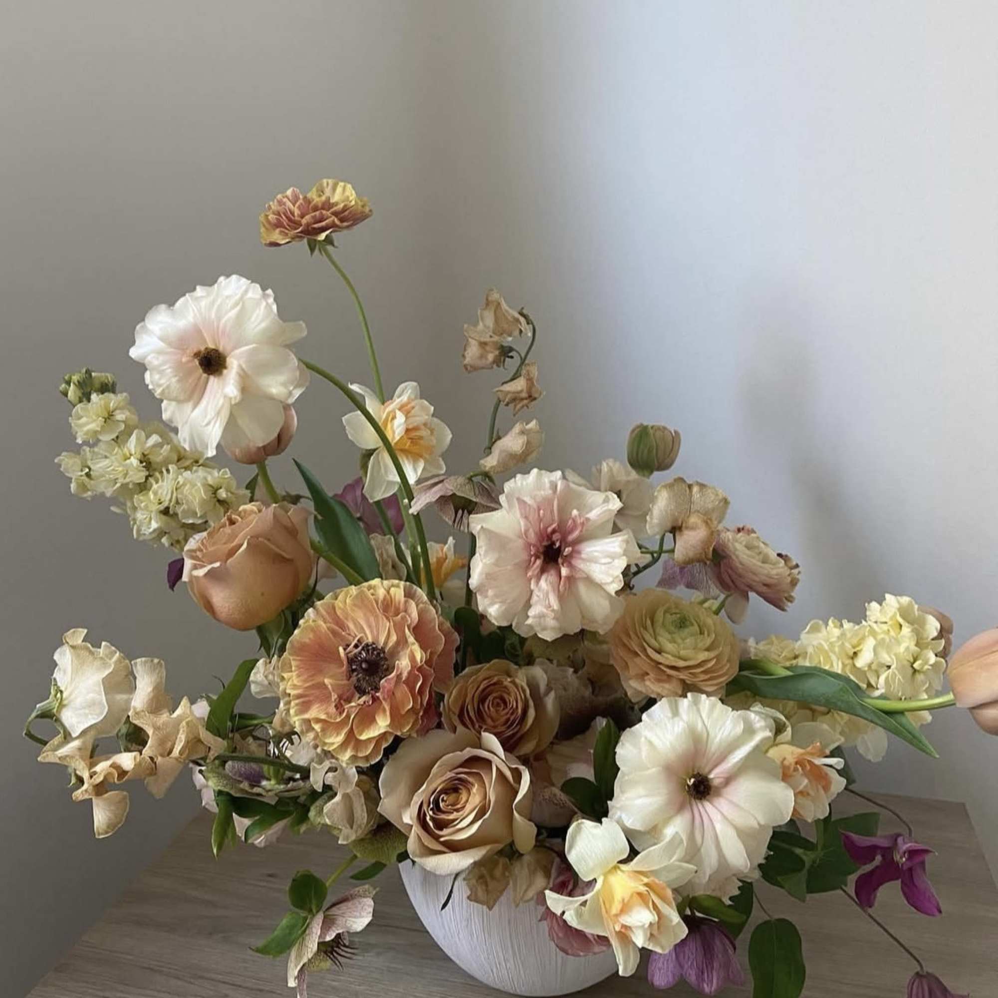Mixed pastel flower arrangement in a white vase on a table