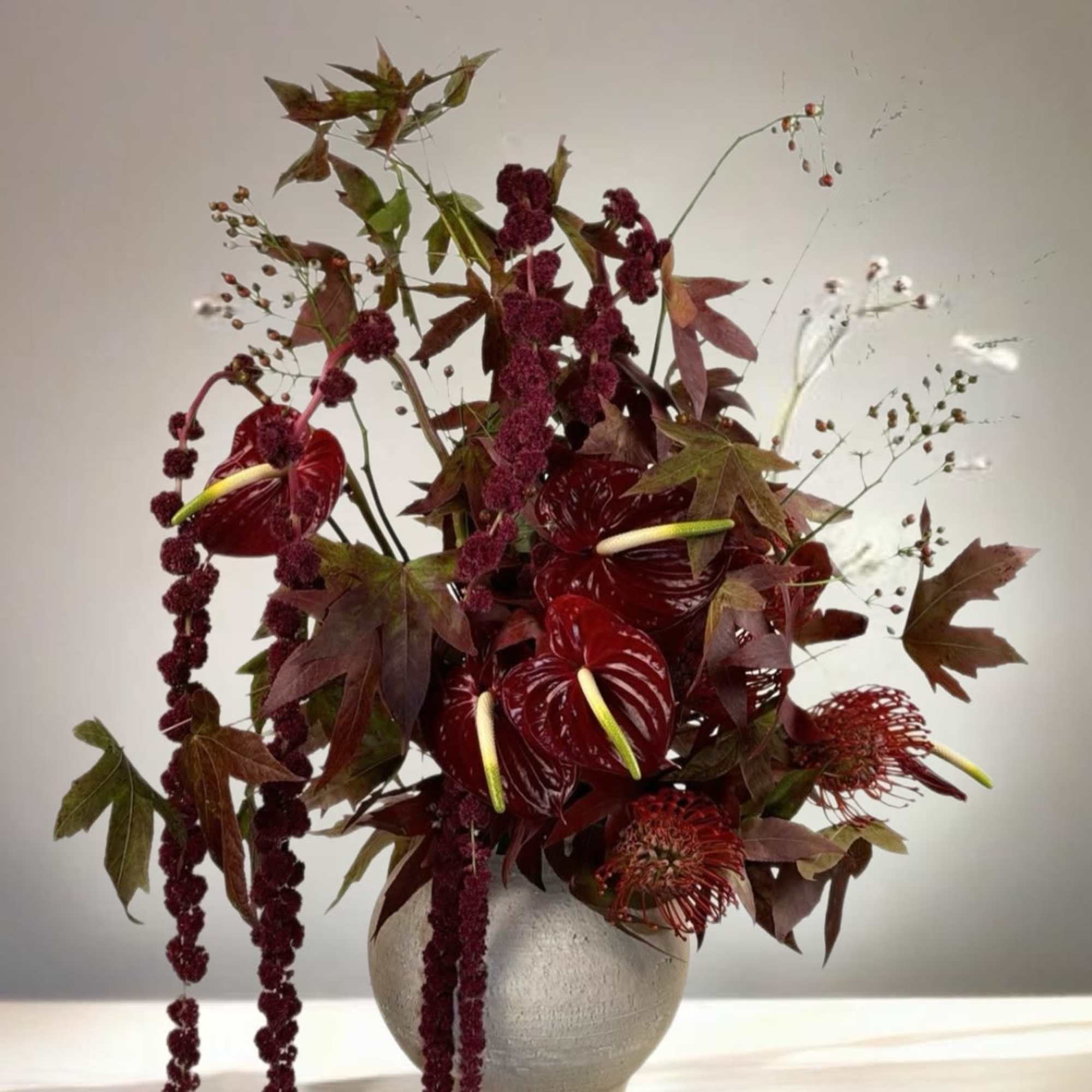 Deep red floral arrangement in a round white vase