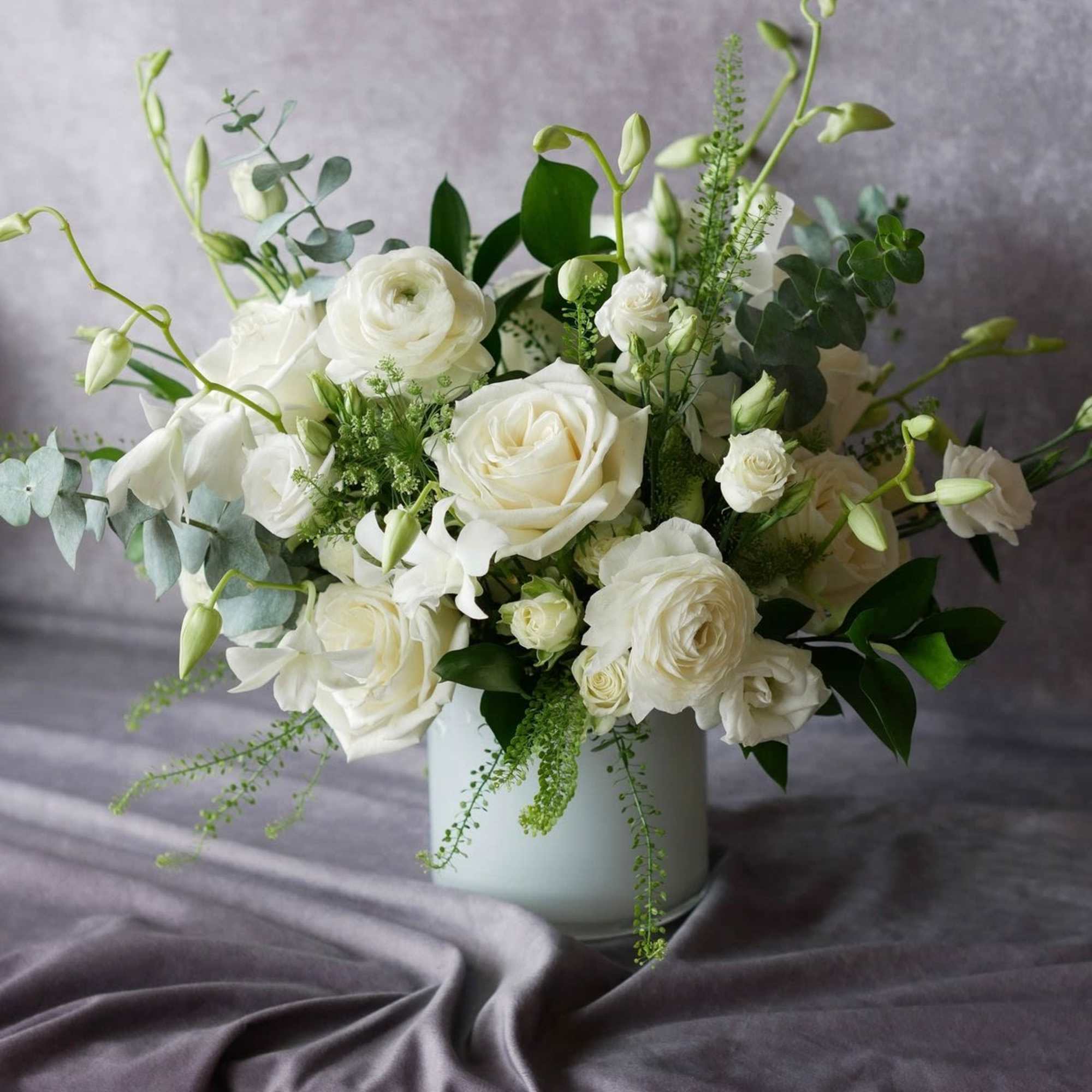 White floral arrangement in a pale vase with eucalyptus accents