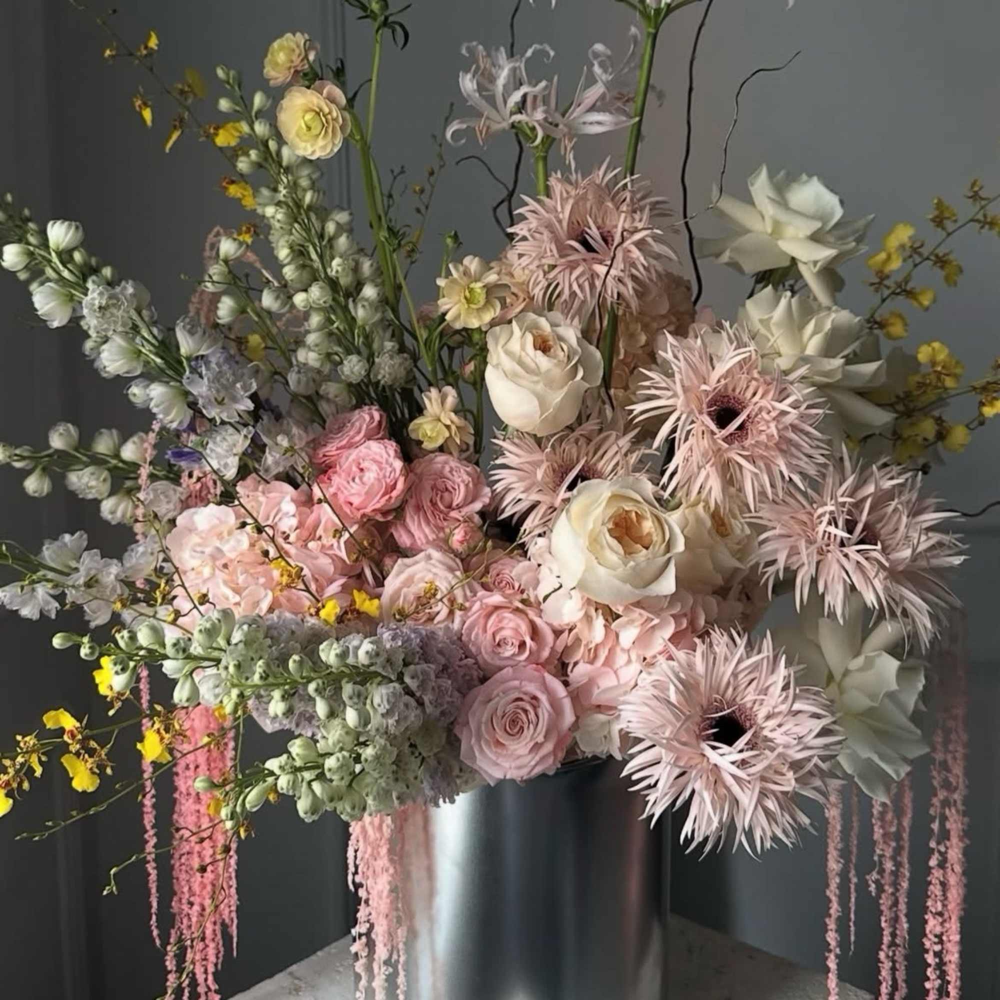 Tall pastel floral arrangement in a silver cylinder vase