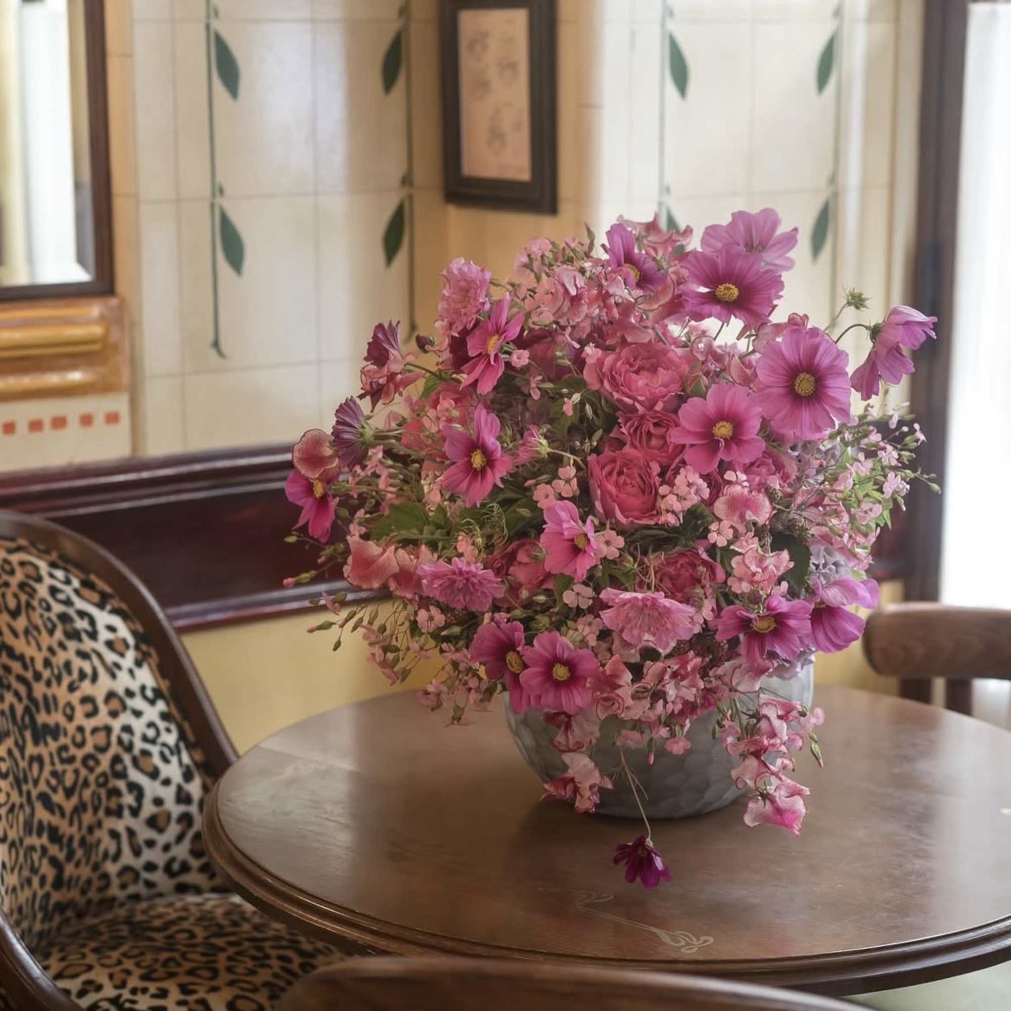Pink mixed flower arrangement in a gray vase on a table