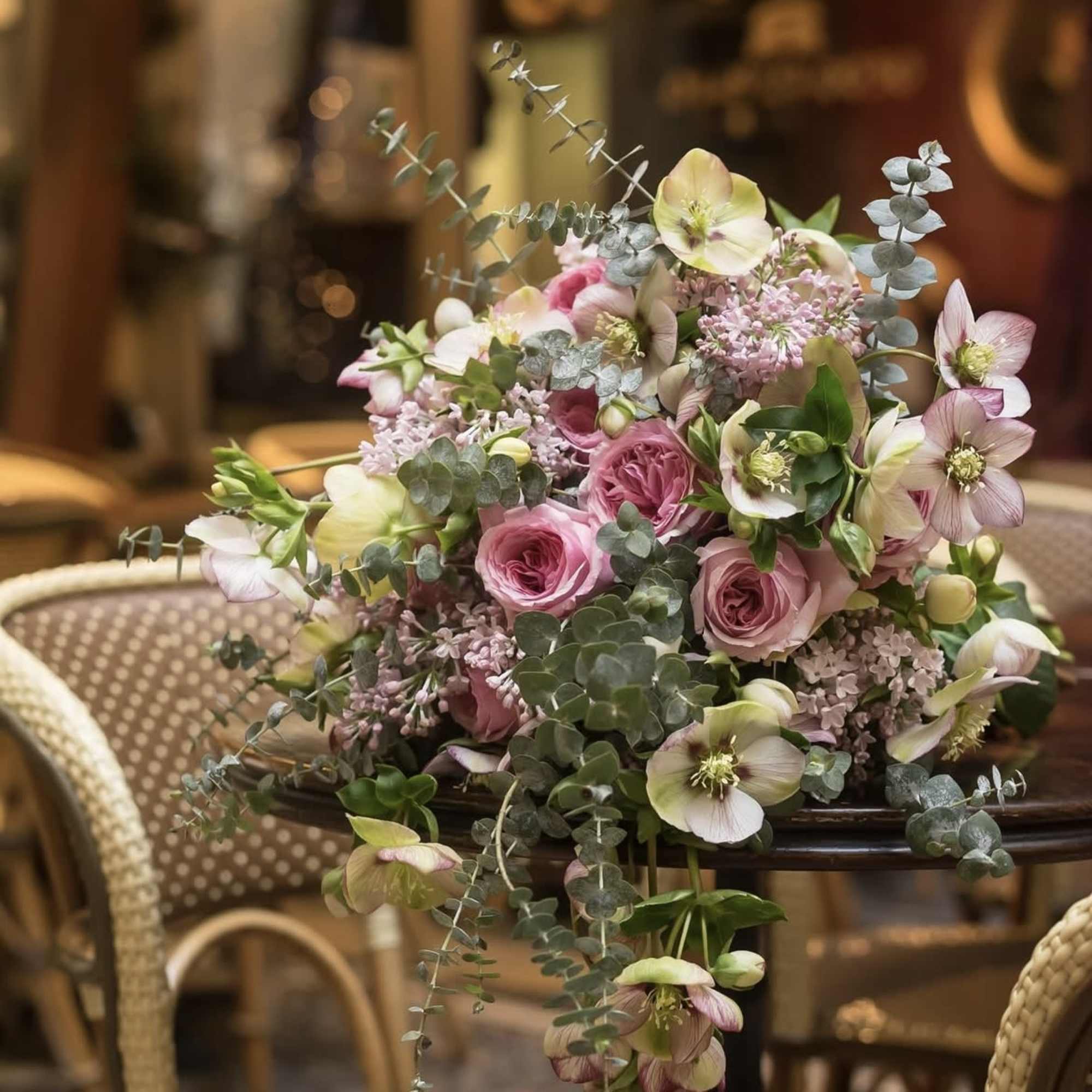 Pink and white floral arrangement with roses and hellebores on a table