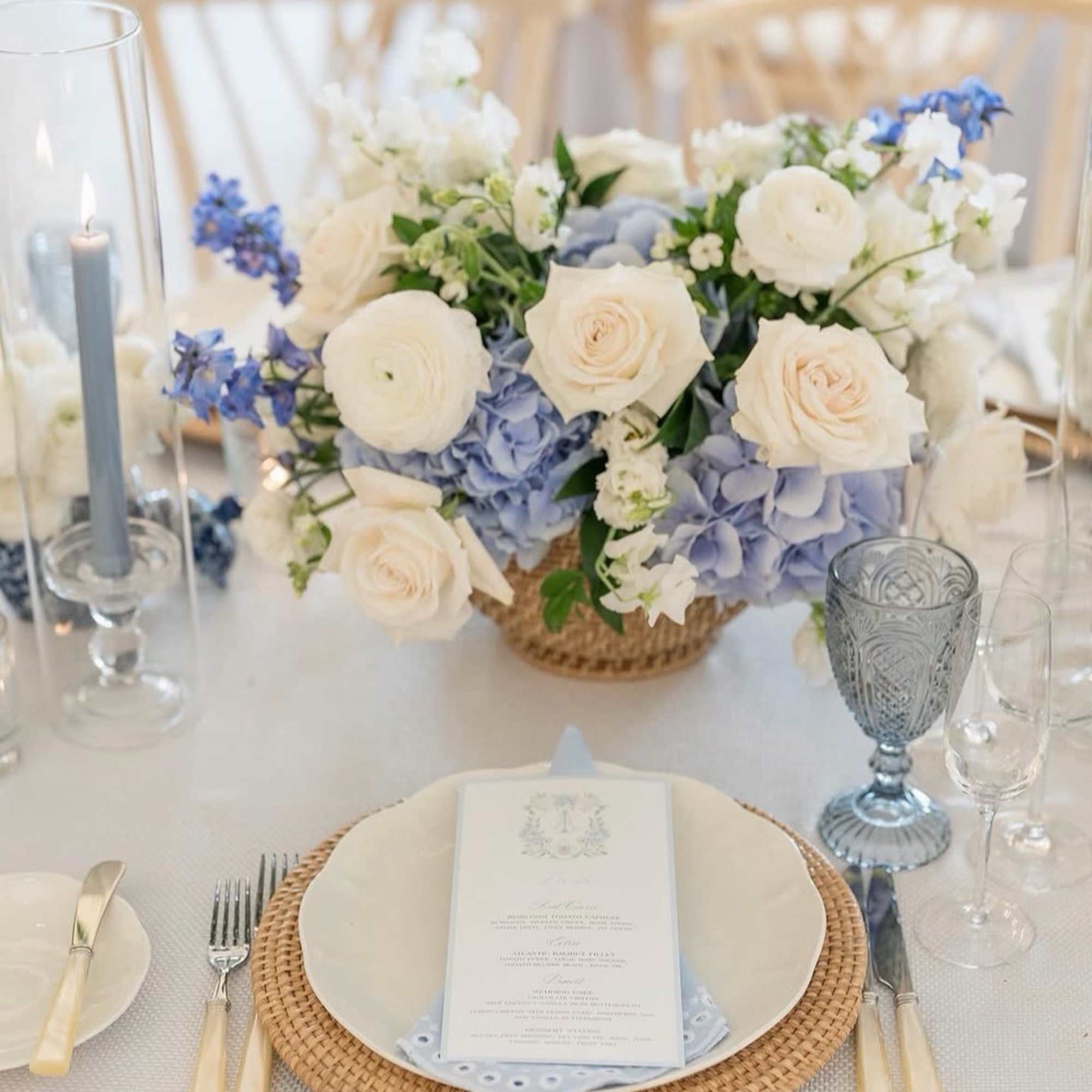 White and pale blue floral centerpiece on a table set for a formal event