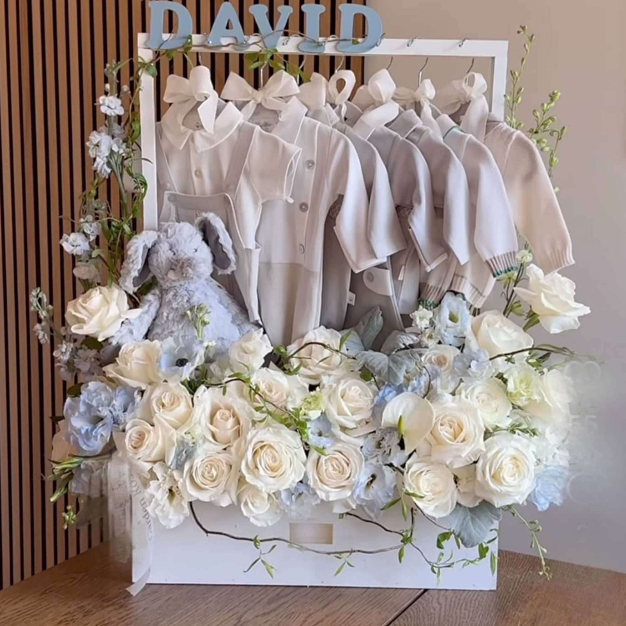 White floral gift box with baby clothes, a plush bunny, and the name David