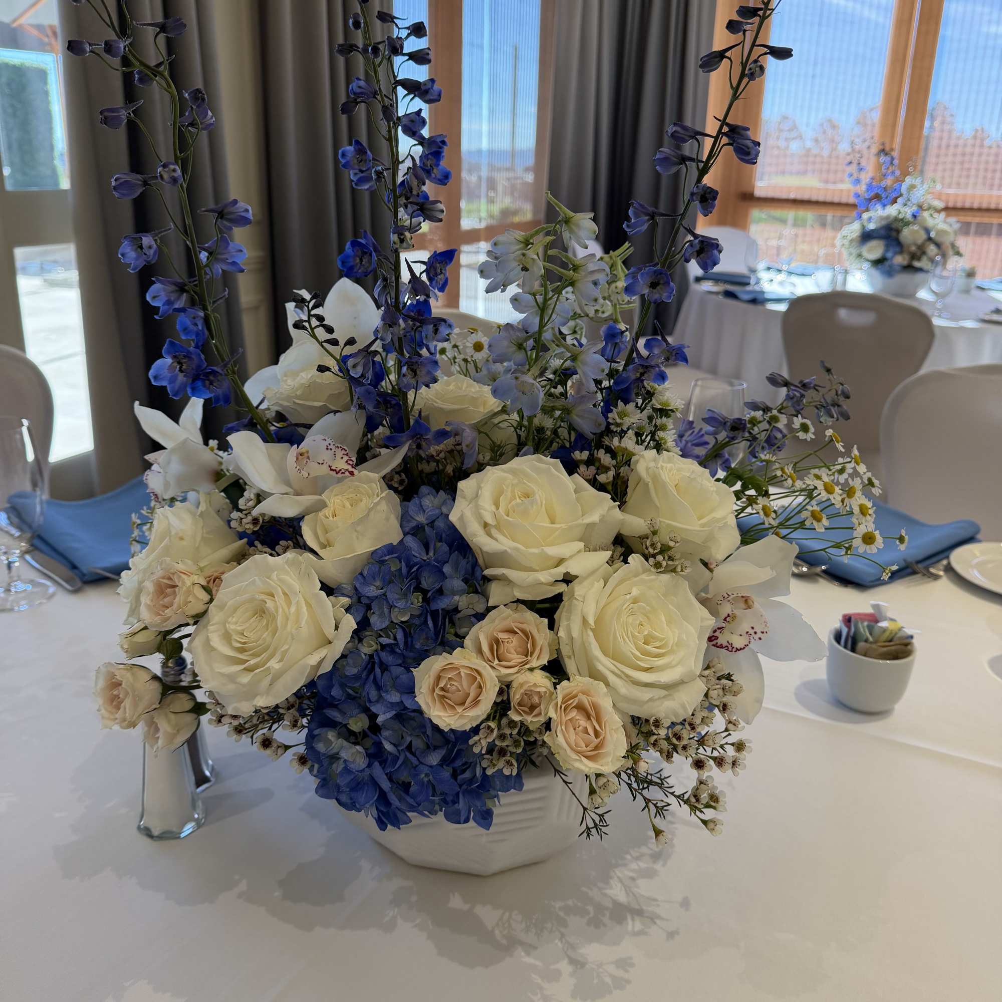Blue and white floral centerpiece in a white vase on a banquet table