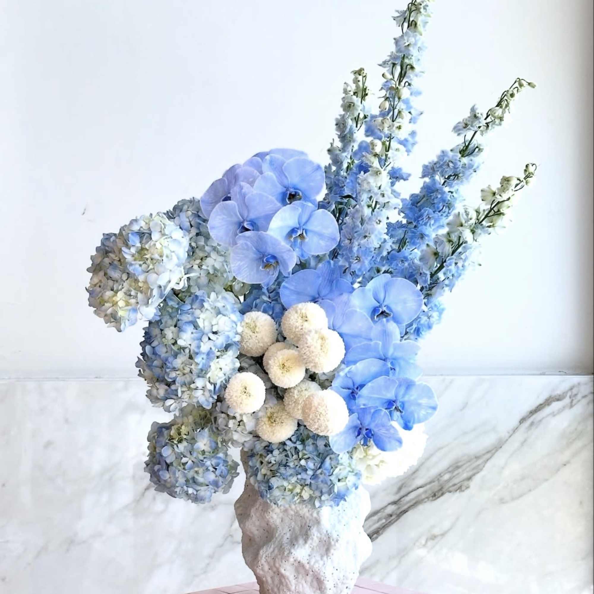 Blue floral arrangement in a textured white vase