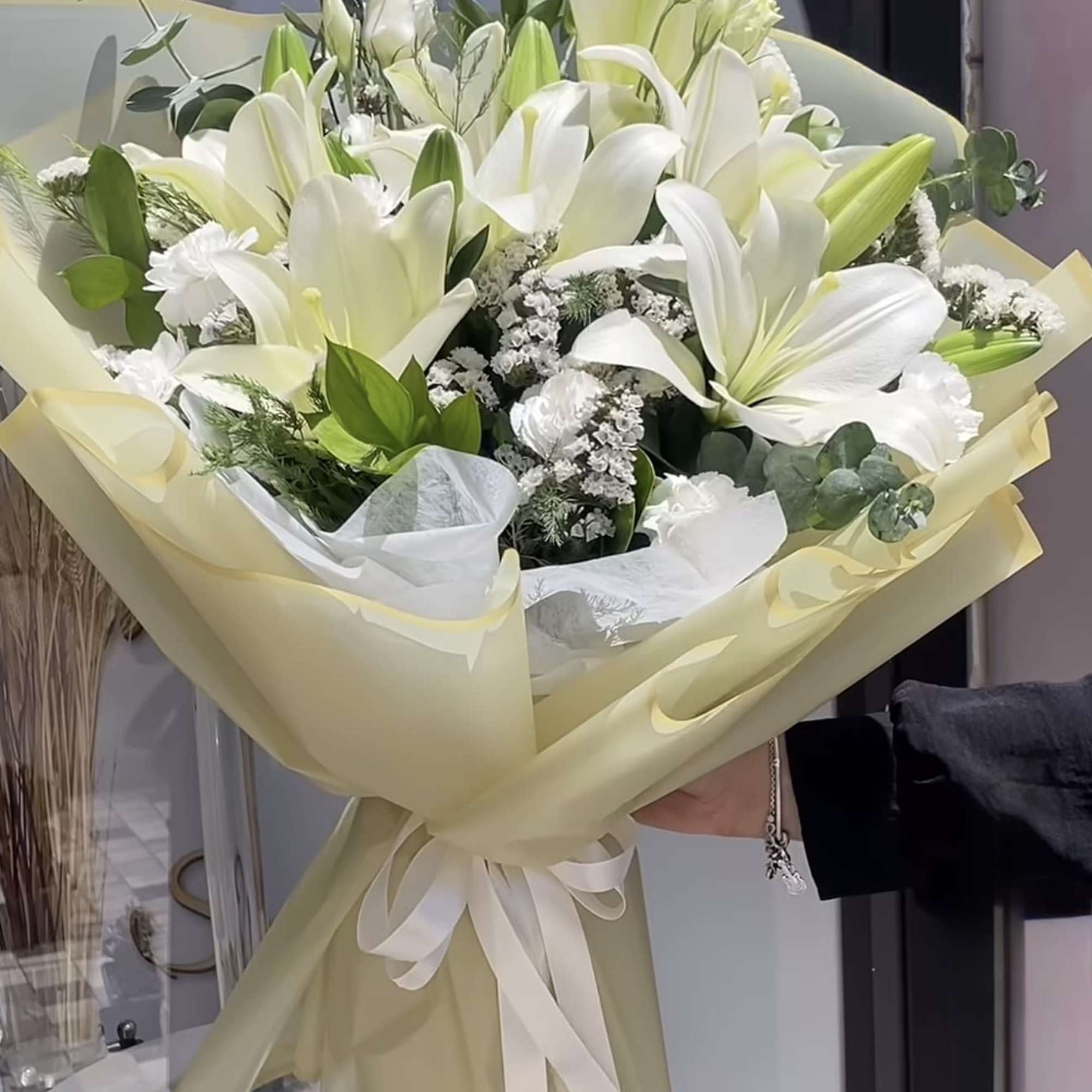 Bouquet of white lilies wrapped in pale yellow paper
