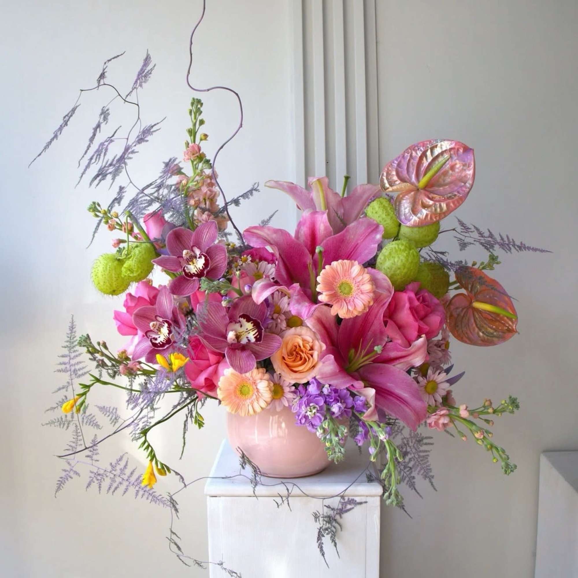 Pink and purple mixed floral arrangement in a pale pink vase