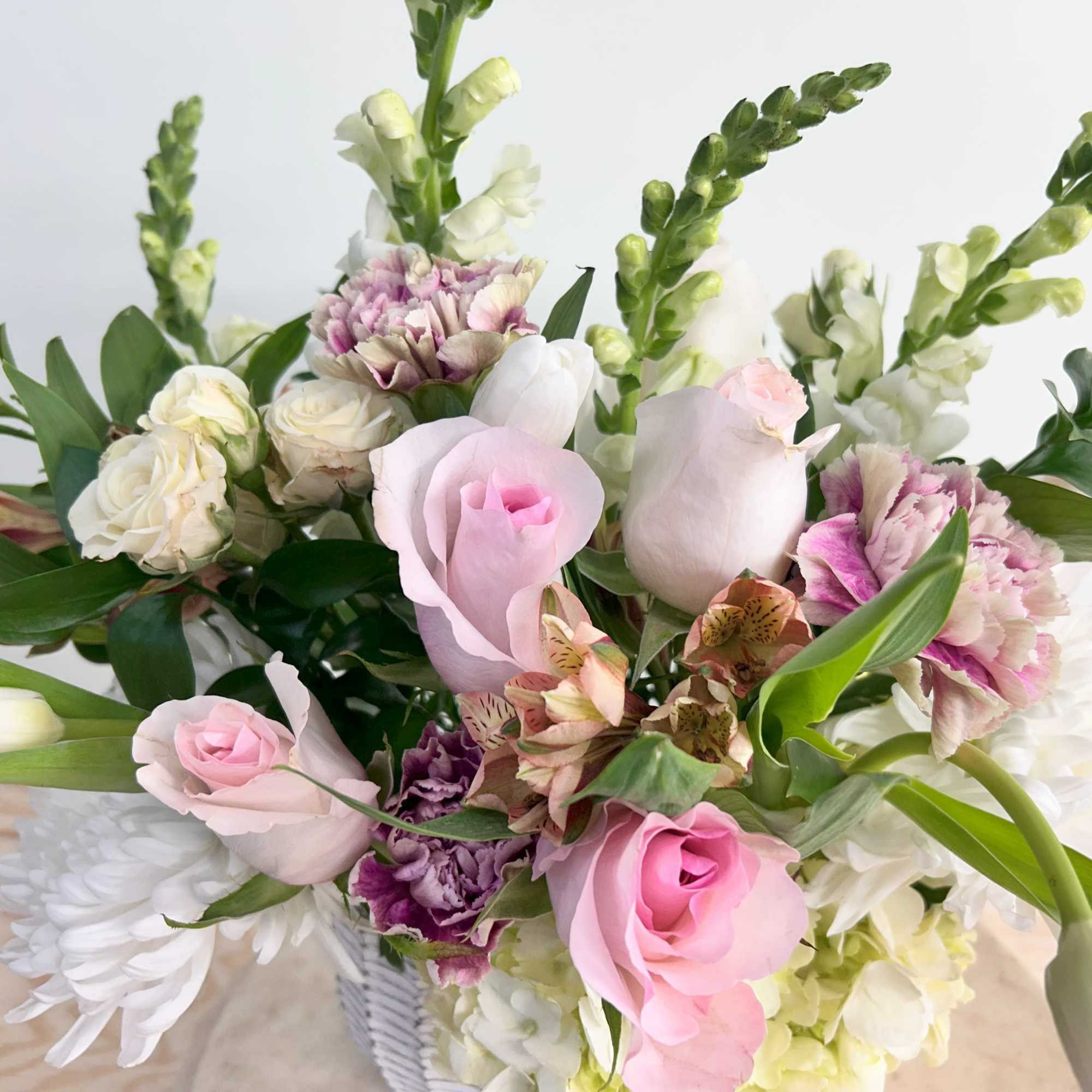 Mixed bouquet of pink and white flowers in a white vase