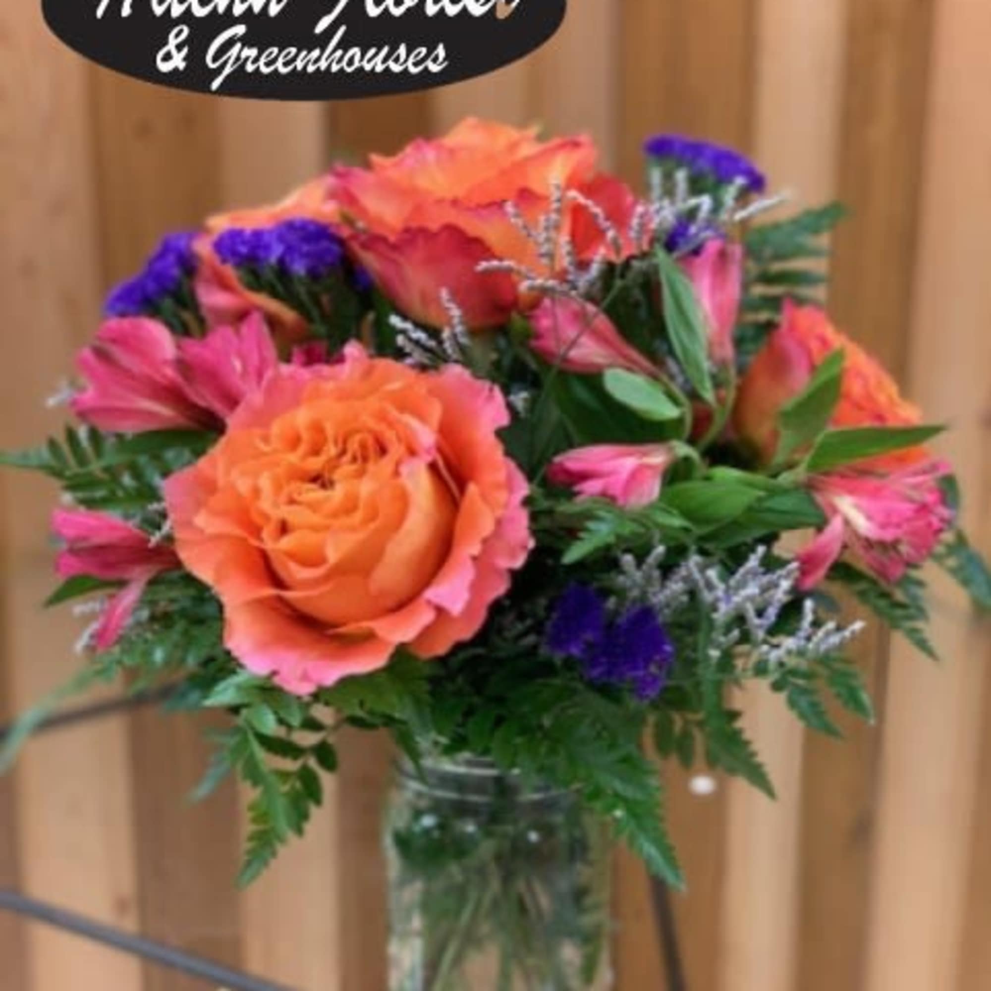 Mixed bouquet of orange, pink, and purple flowers in a glass vase