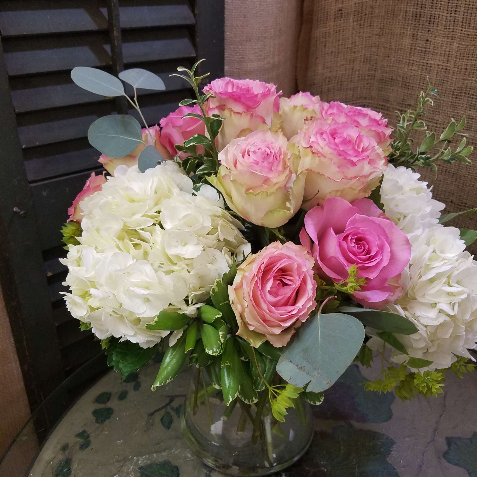 Pink roses and white hydrangeas arranged in a clear glass vase