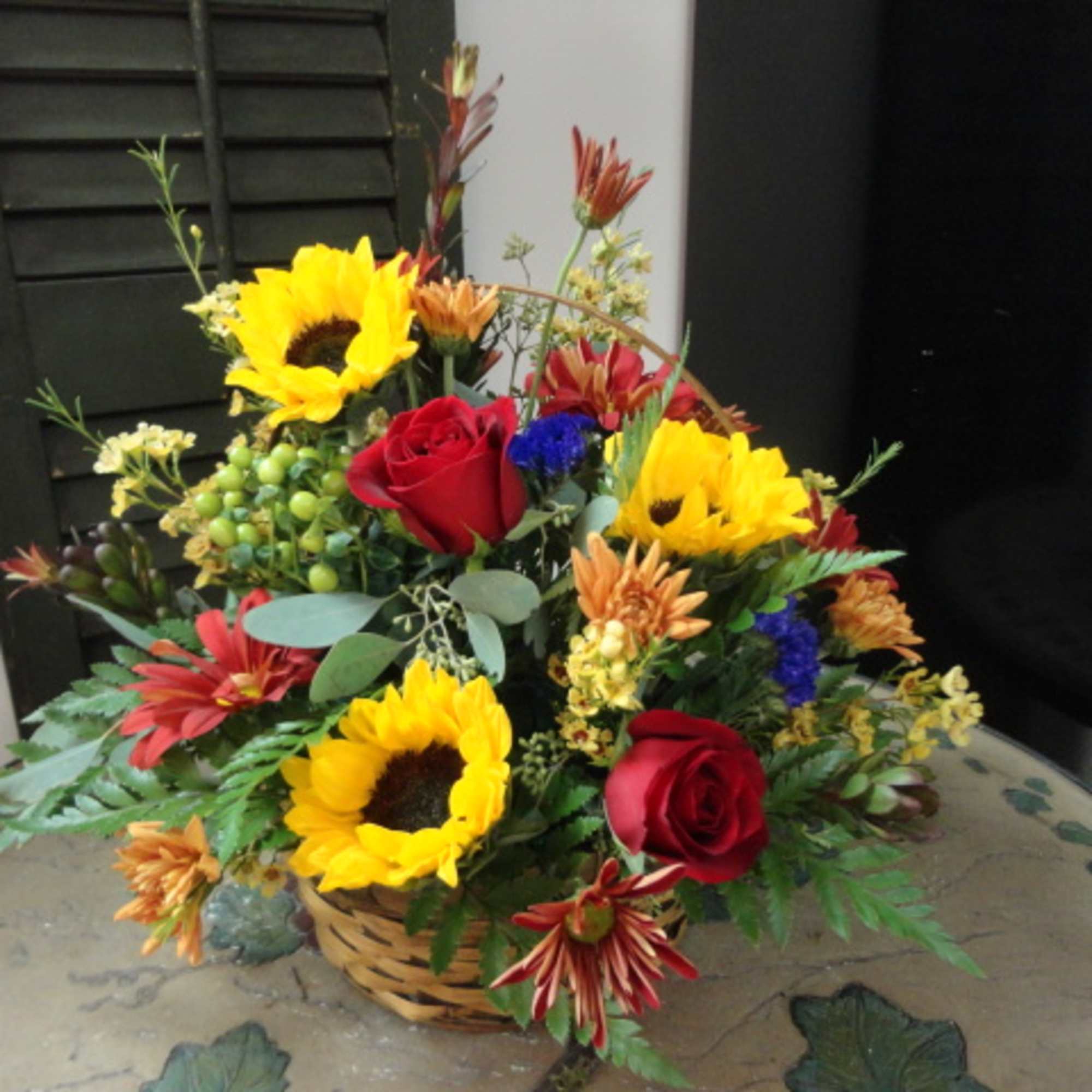 Basket arrangement with sunflowers, red roses, and mixed flowers