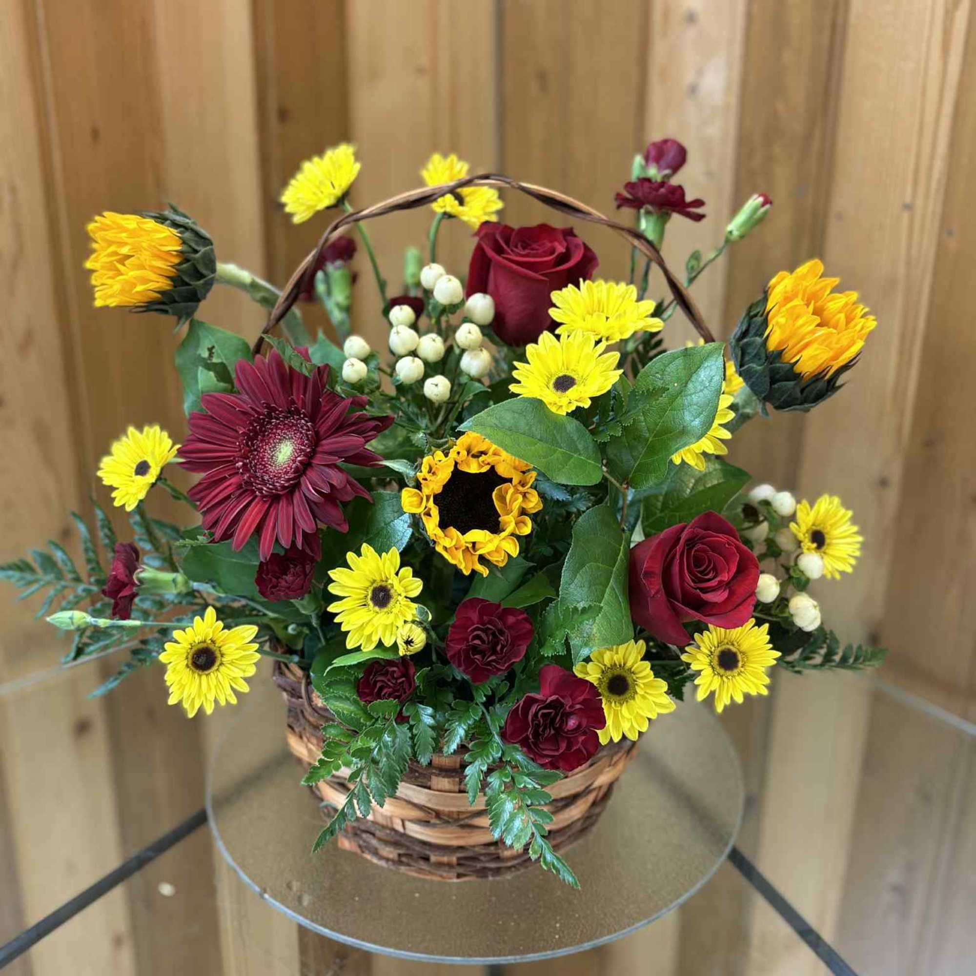 Basket arrangement of red roses and yellow daisies