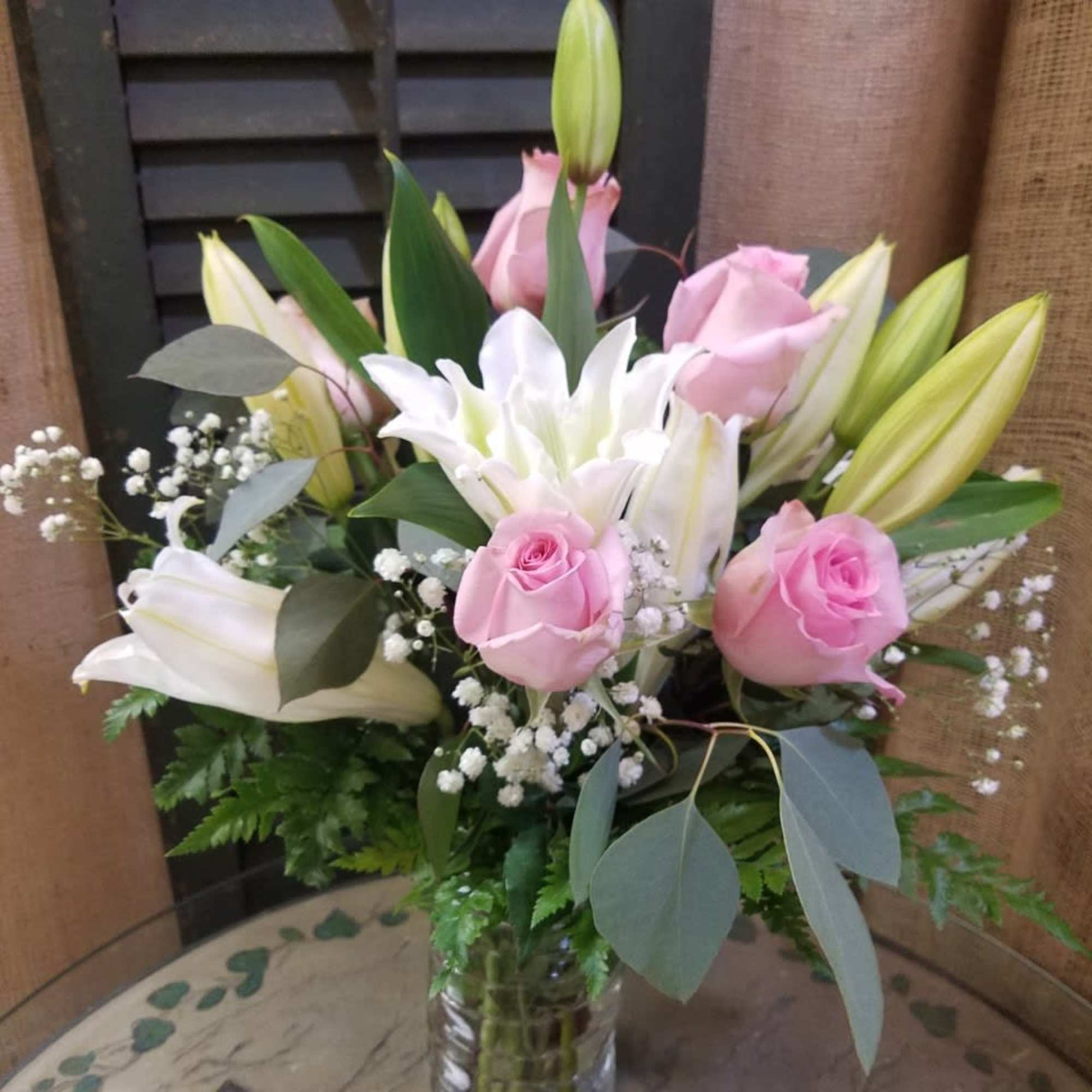 Pink roses and white lilies with baby's breath in a clear glass vase