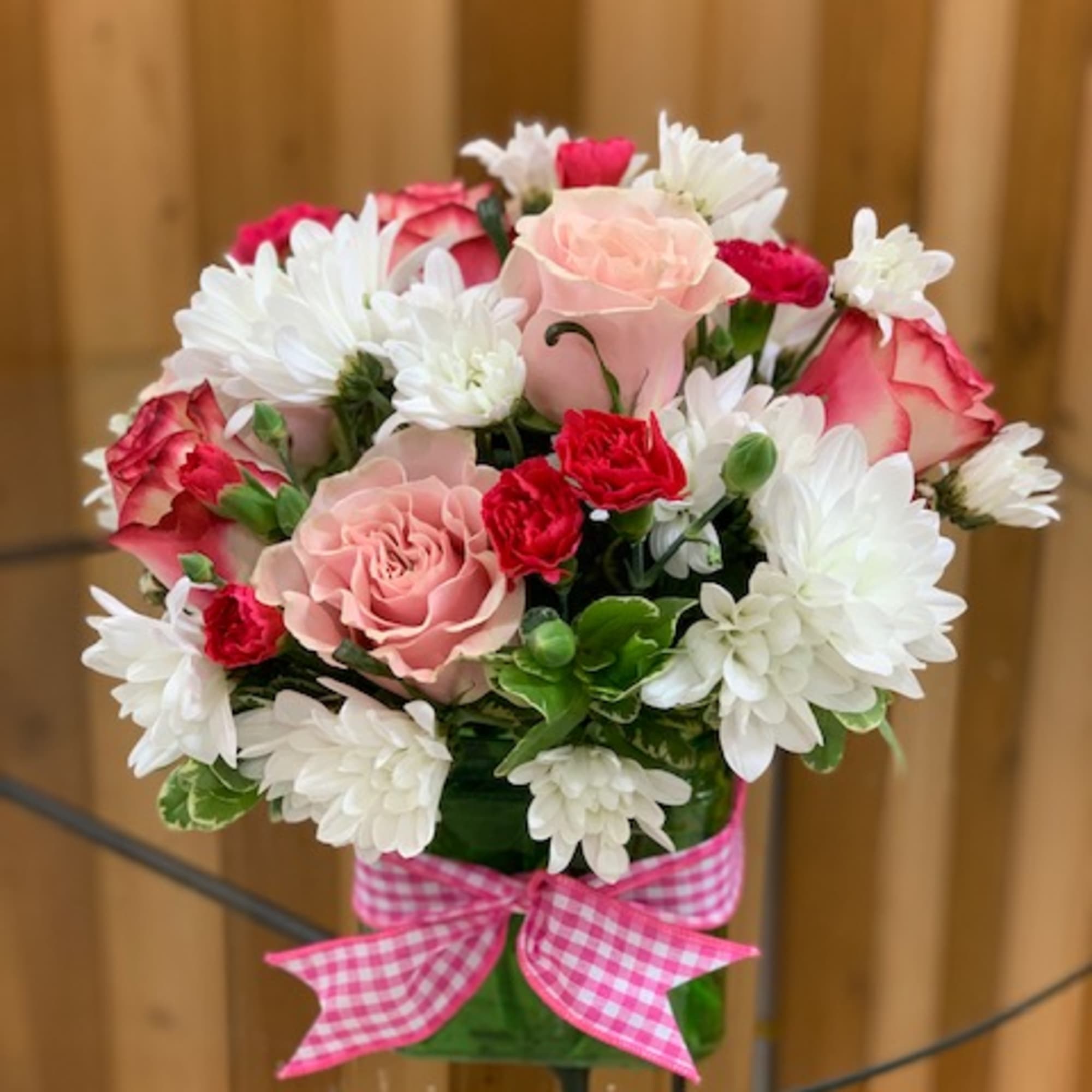 Pink and white flower bouquet in a glass vase with a gingham ribbon