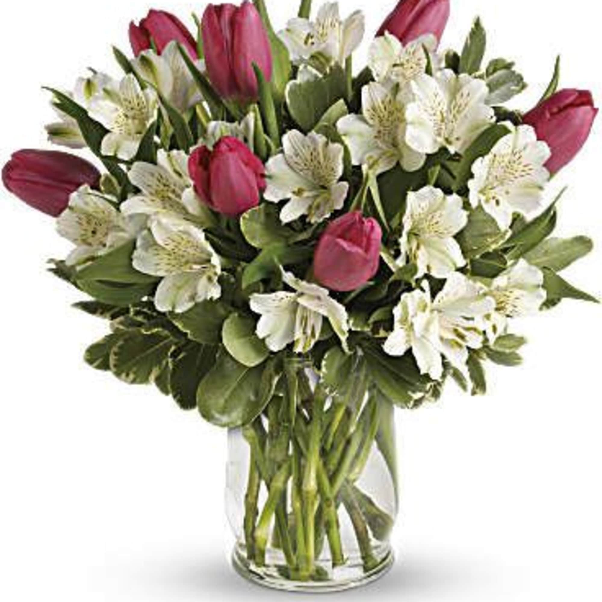 Pink tulips and white alstroemeria arranged in a clear glass vase