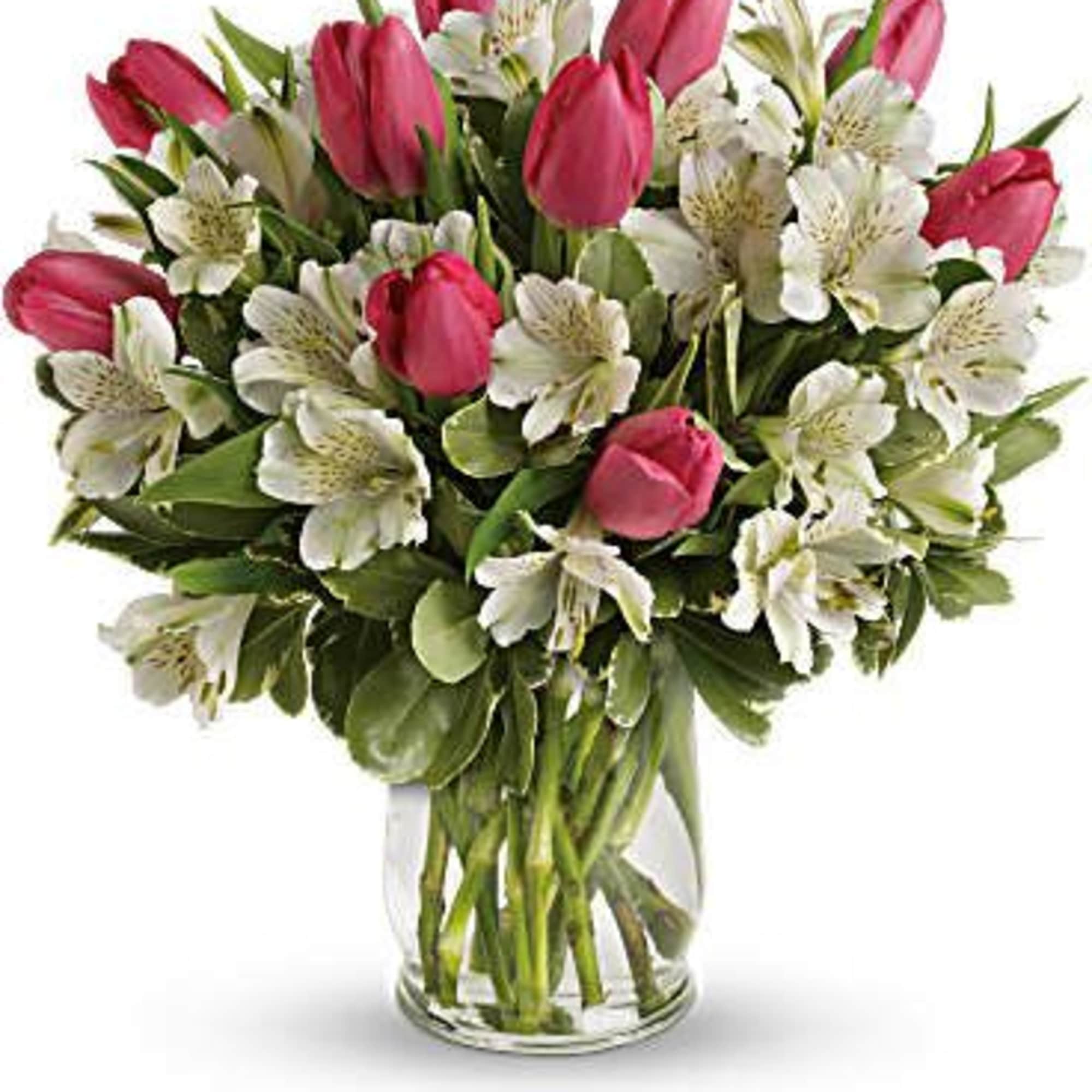 Arrangement of pink tulips and white alstroemeria in a clear glass vase