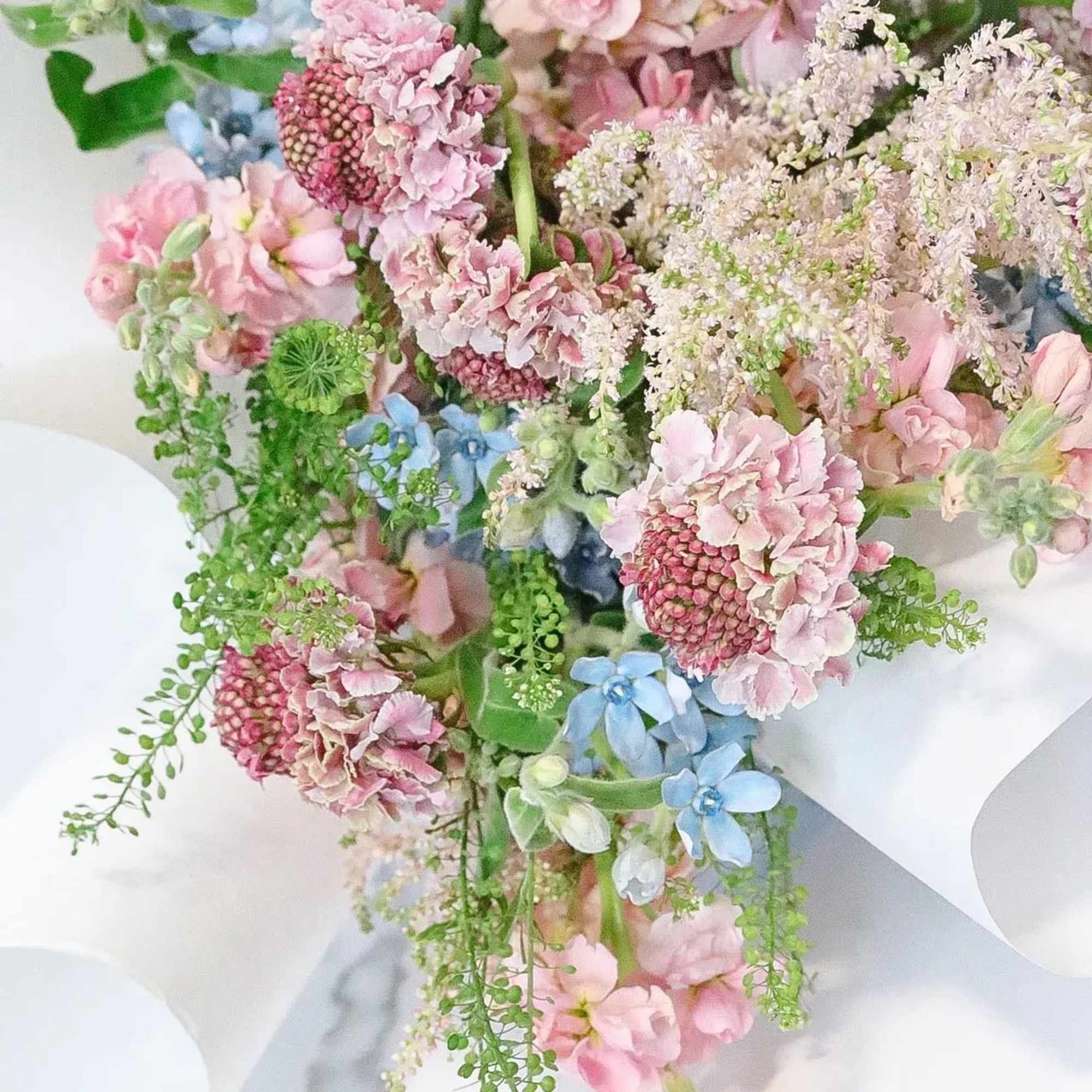 Pastel bouquet with pink and blue flowers wrapped in white paper