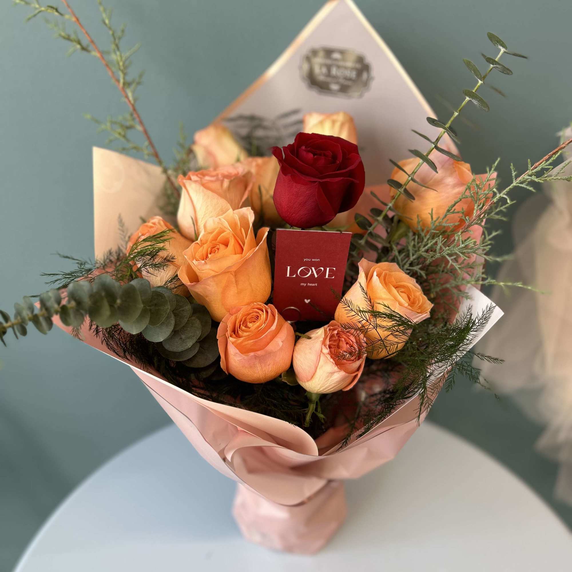 Bouquet of peach and red roses wrapped in pink paper