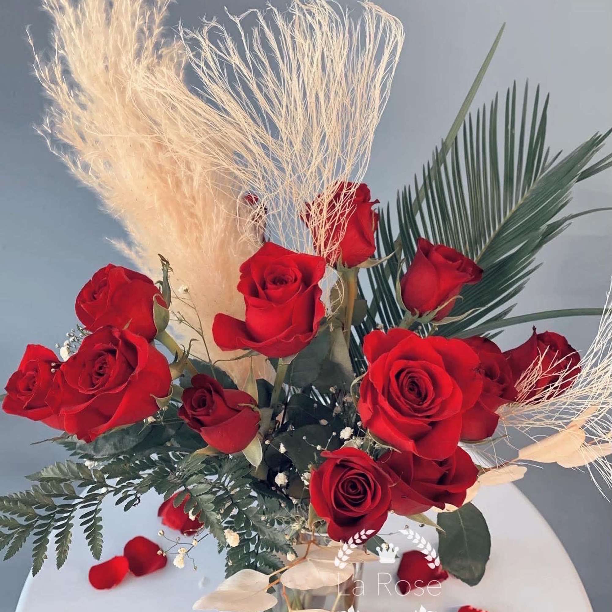 Bouquet of red roses with dried pampas grass and palm fronds