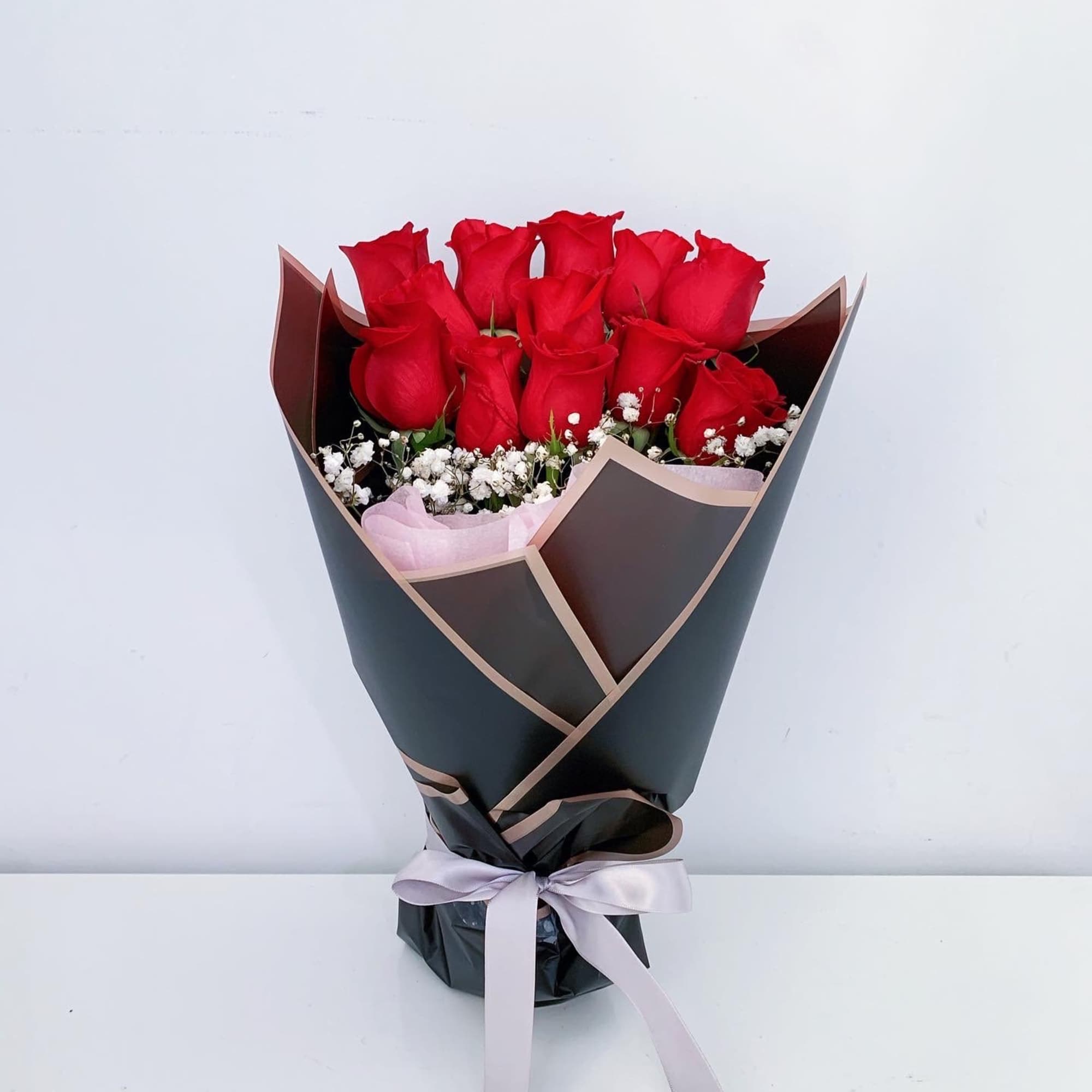 Bouquet of red roses with white baby's breath in black wrap