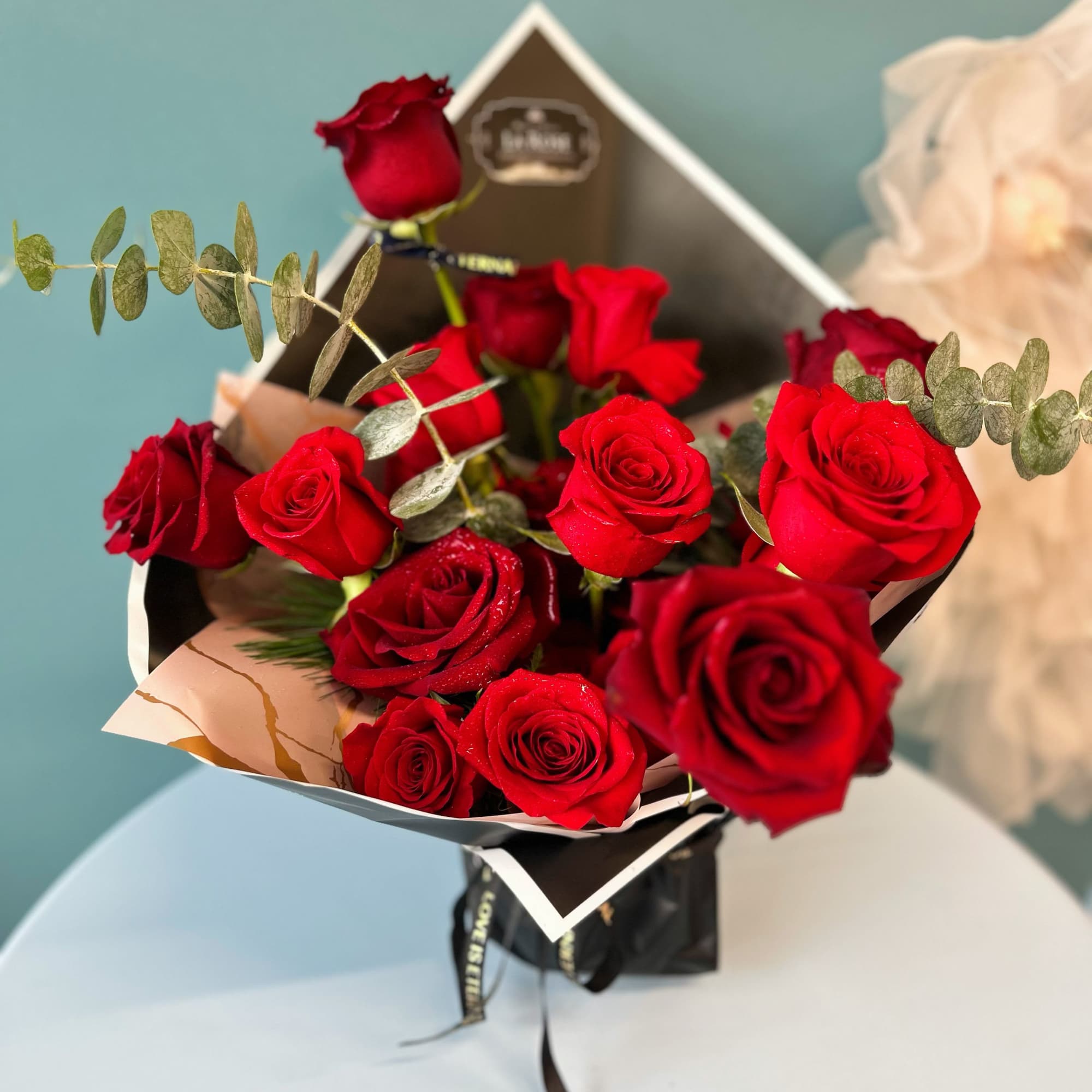 Bouquet of red roses with eucalyptus in black wrapping