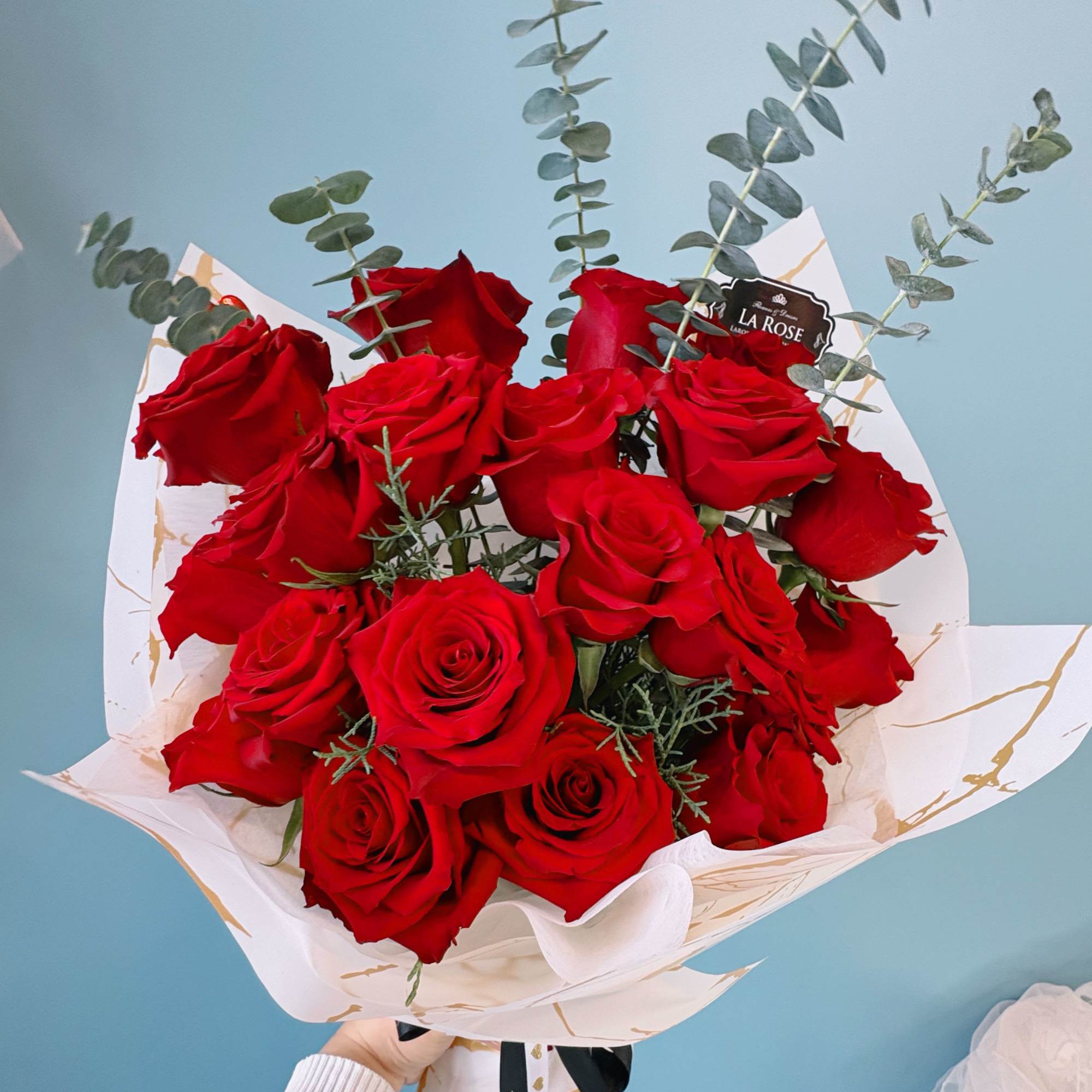 Bouquet of red roses with eucalyptus in white wrap