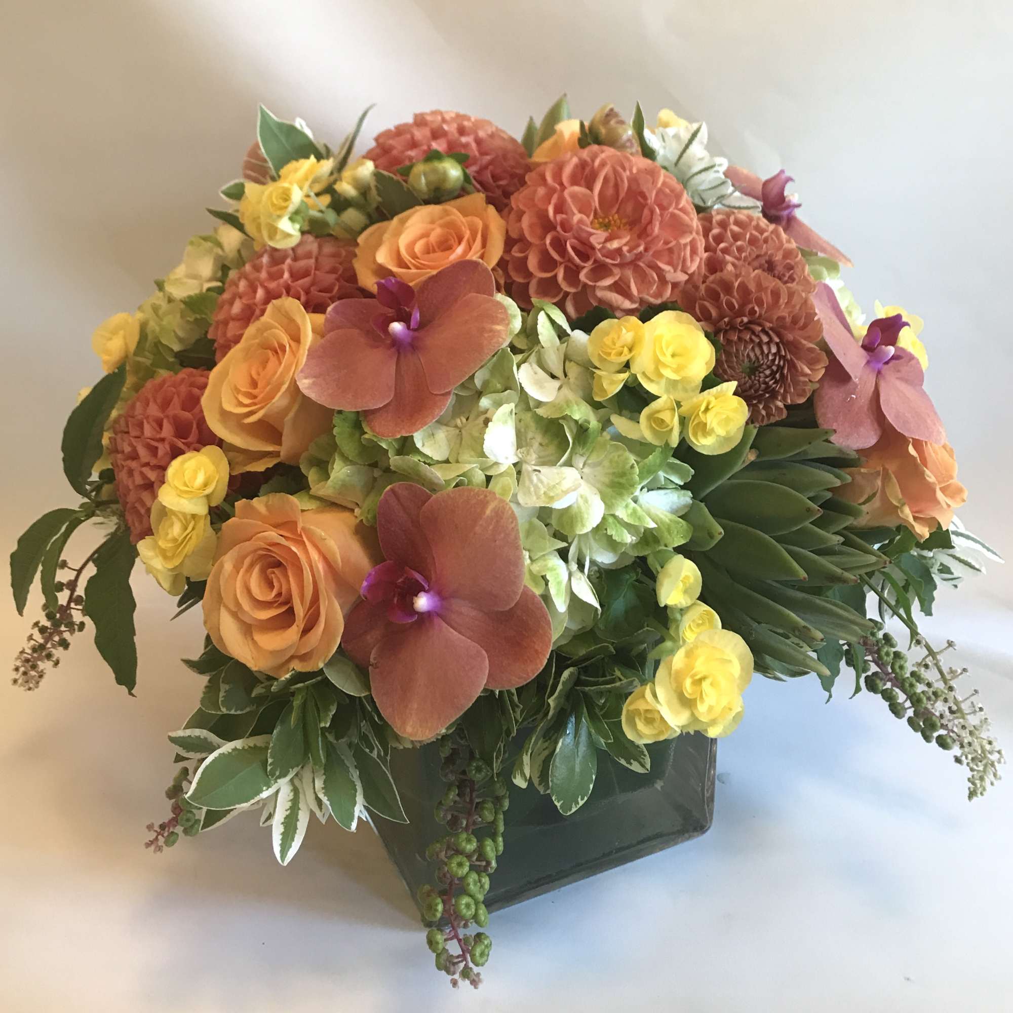 Mixed bouquet of orange, yellow, and pink flowers in a dark vase