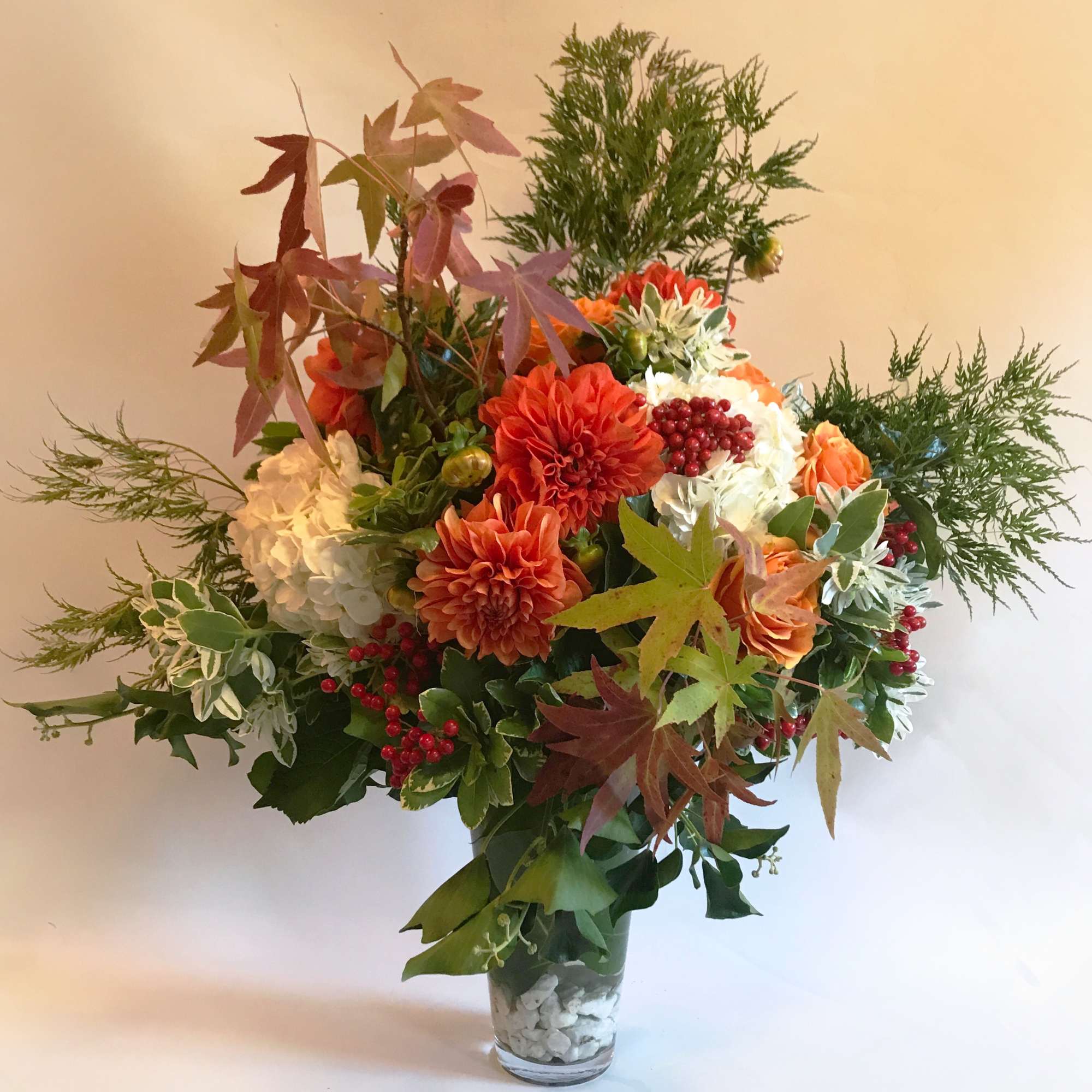 Autumn bouquet of orange and white flowers in a clear glass vase