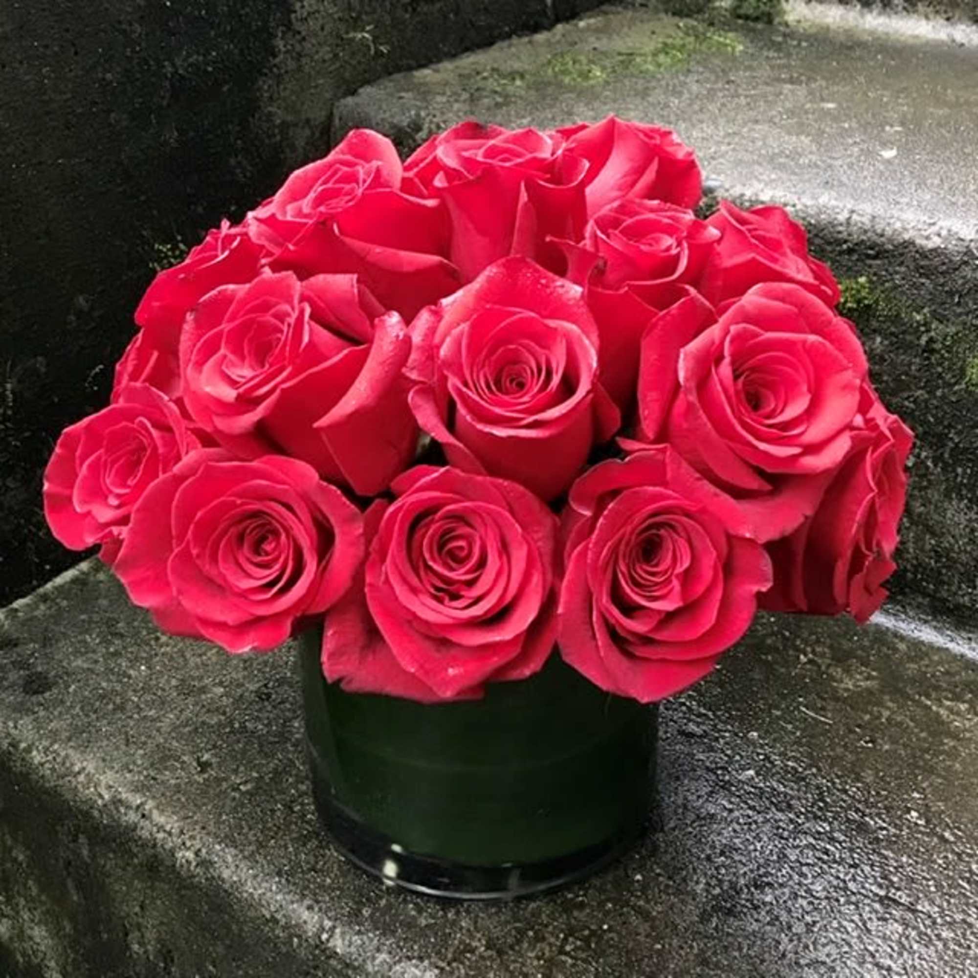 Bouquet of bright pink roses in a dark glass vase