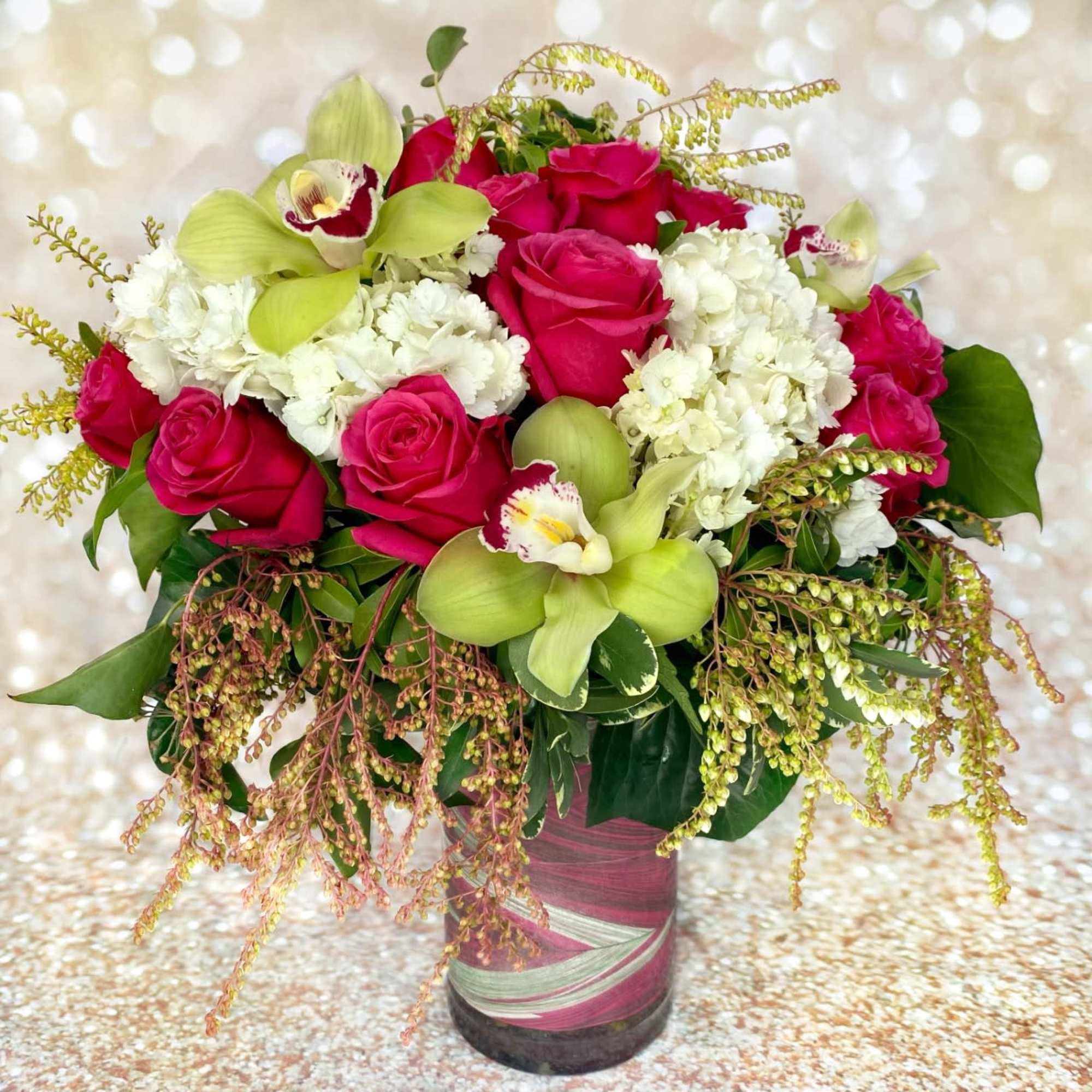 Pink roses and white hydrangeas in a glass vase with green orchids