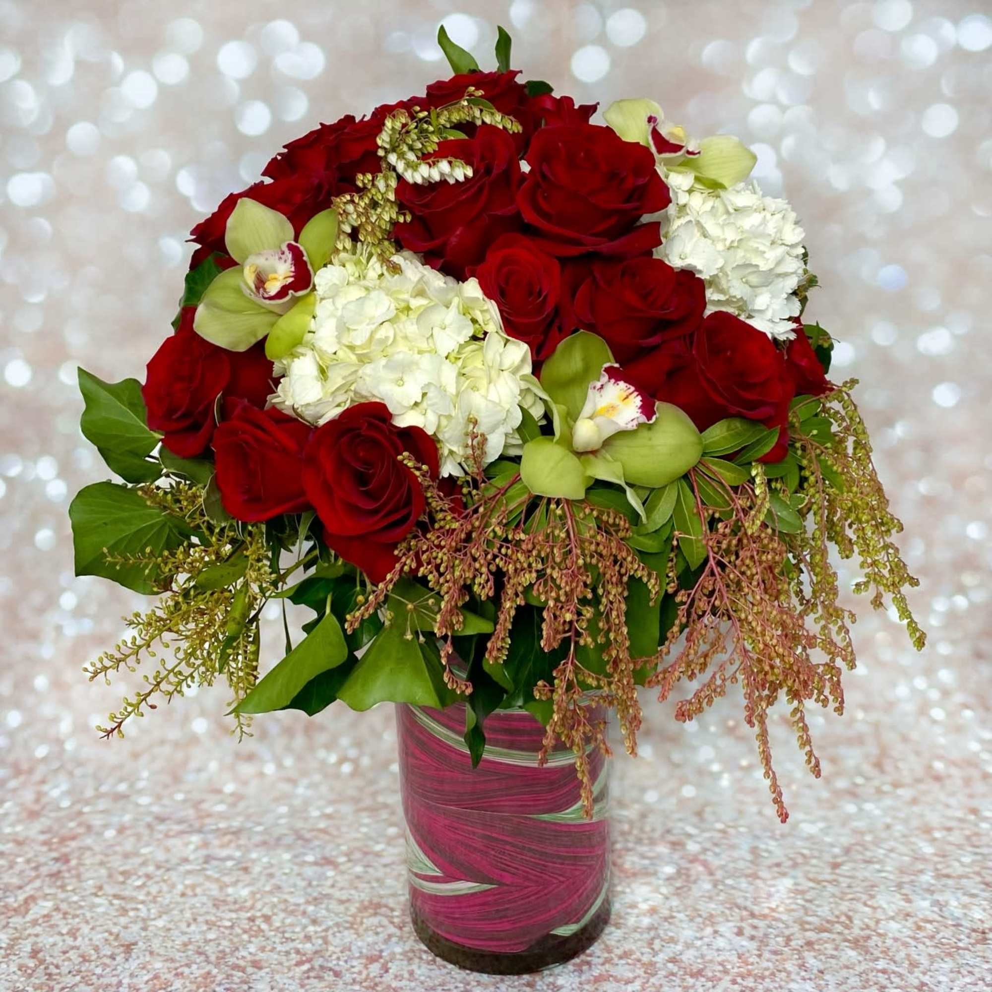 Red roses and white hydrangeas in a pink glass vase