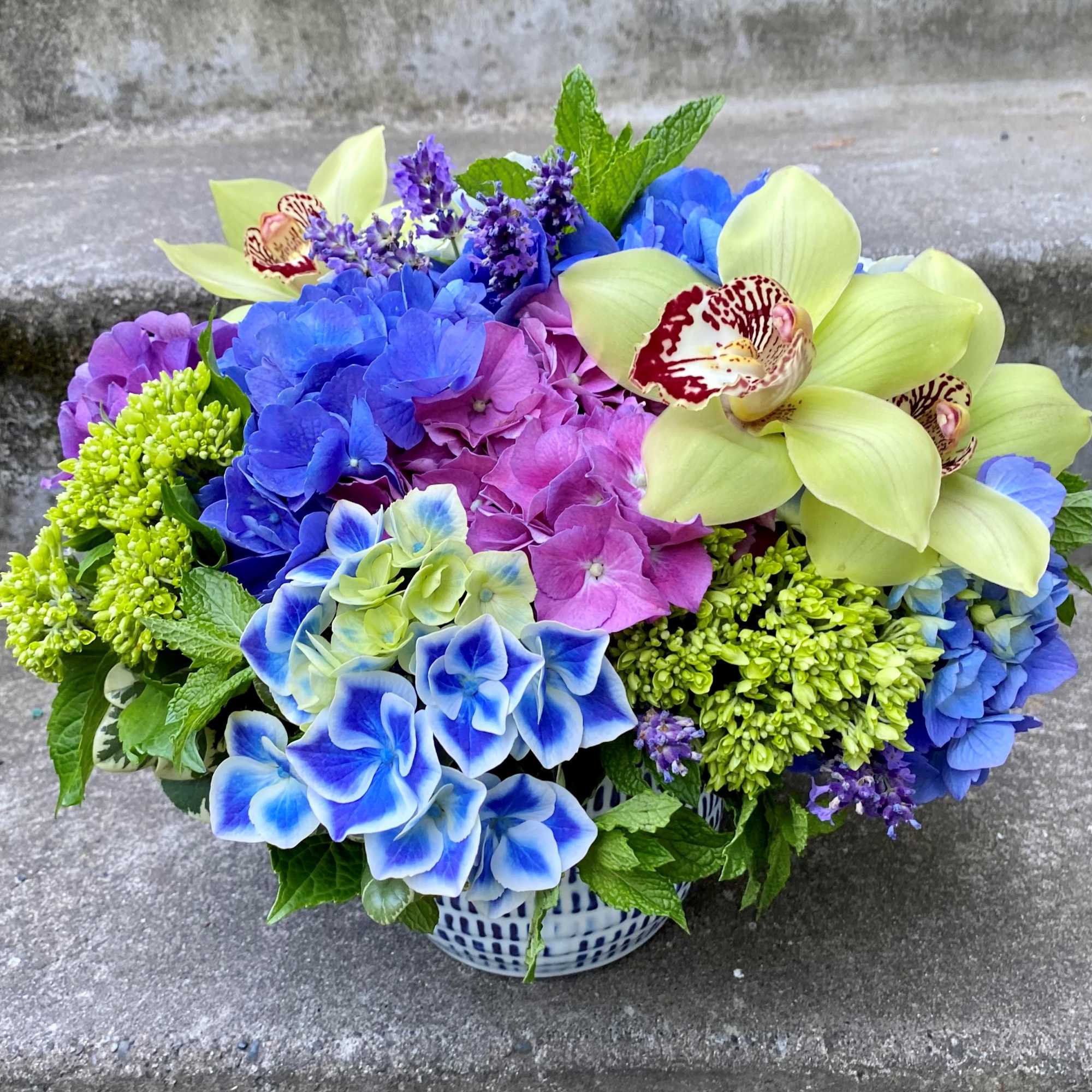 Colorful bouquet of blue, purple, and yellow flowers in a patterned vase