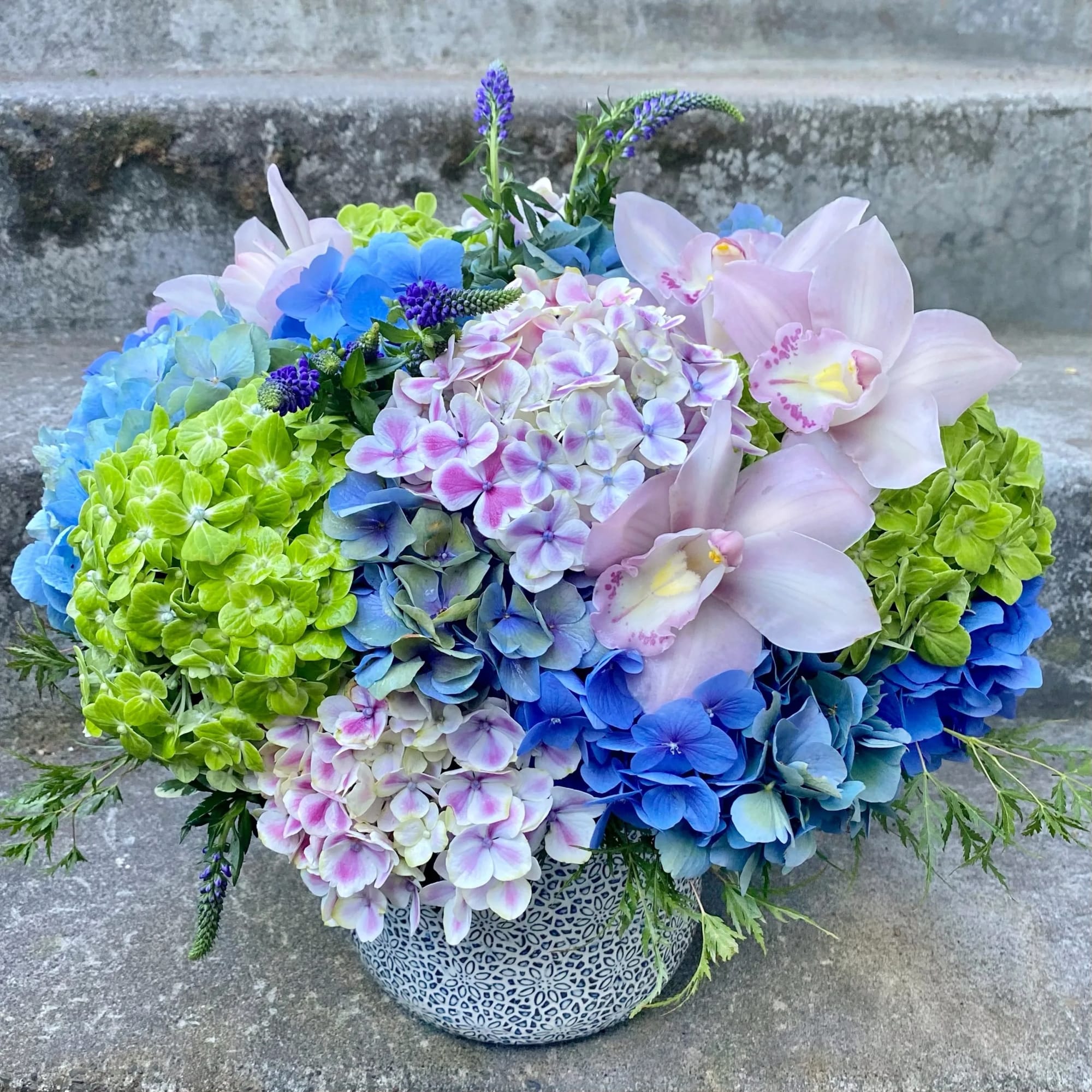 Colorful hydrangea and orchid arrangement in a patterned pot