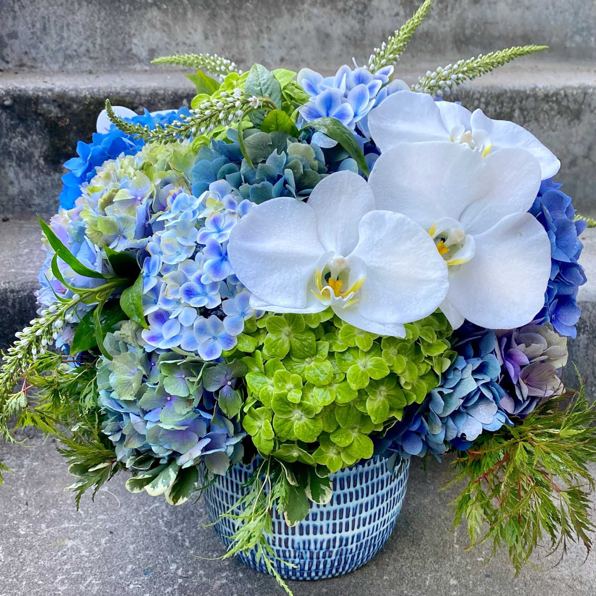 Blue and white floral arrangement in a patterned vase