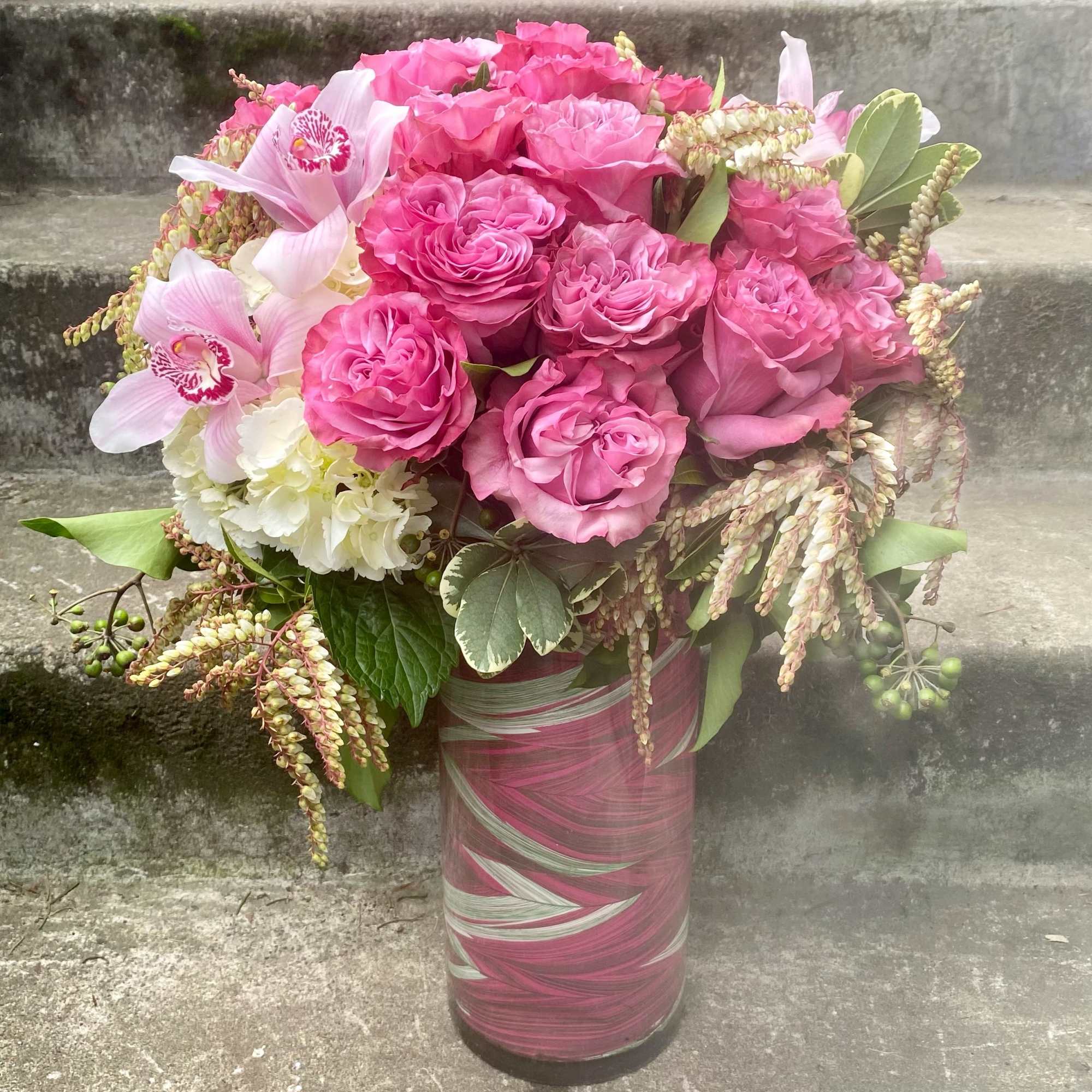 Pink rose bouquet with orchids in a tall glass vase