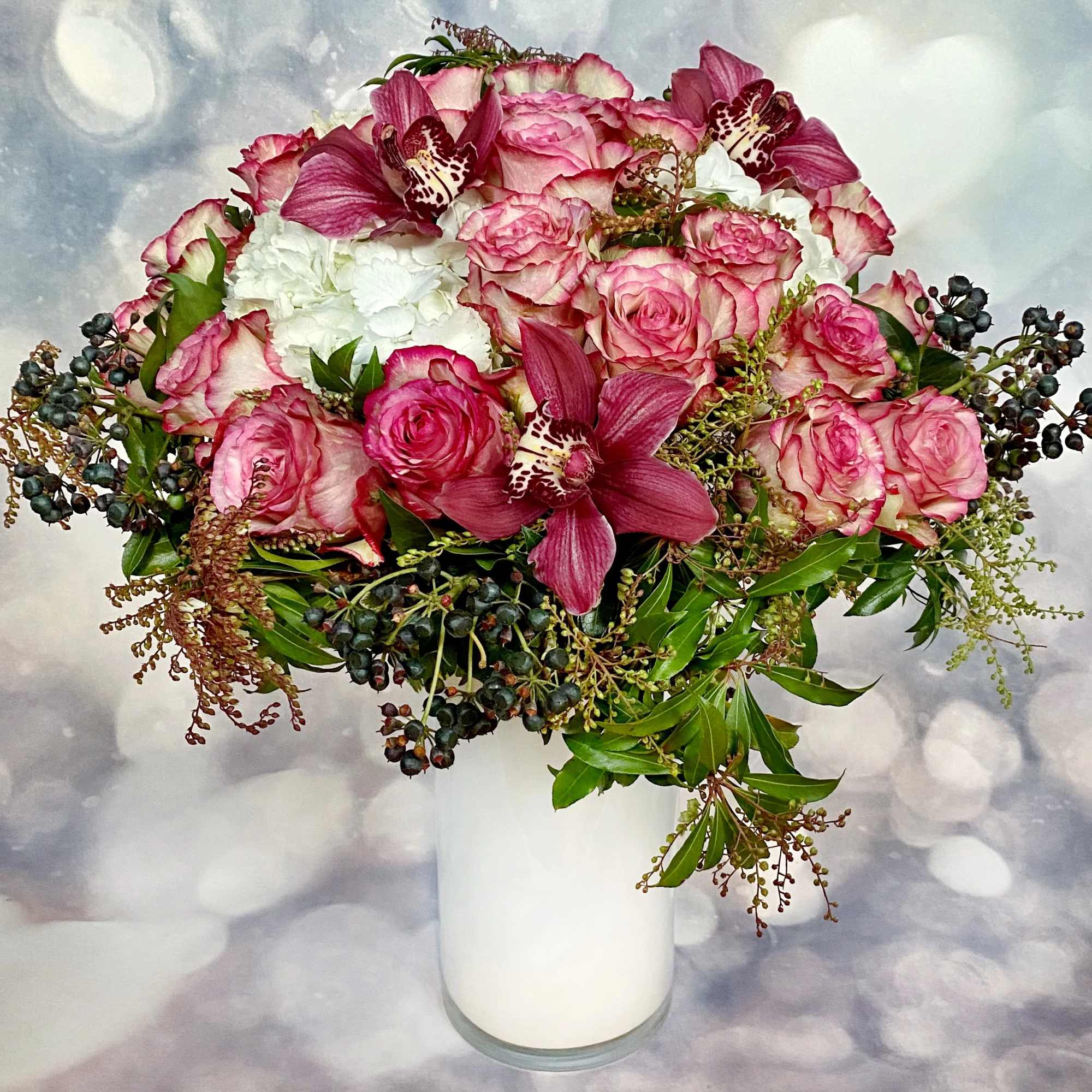 Pink roses and orchids arranged in a white vase