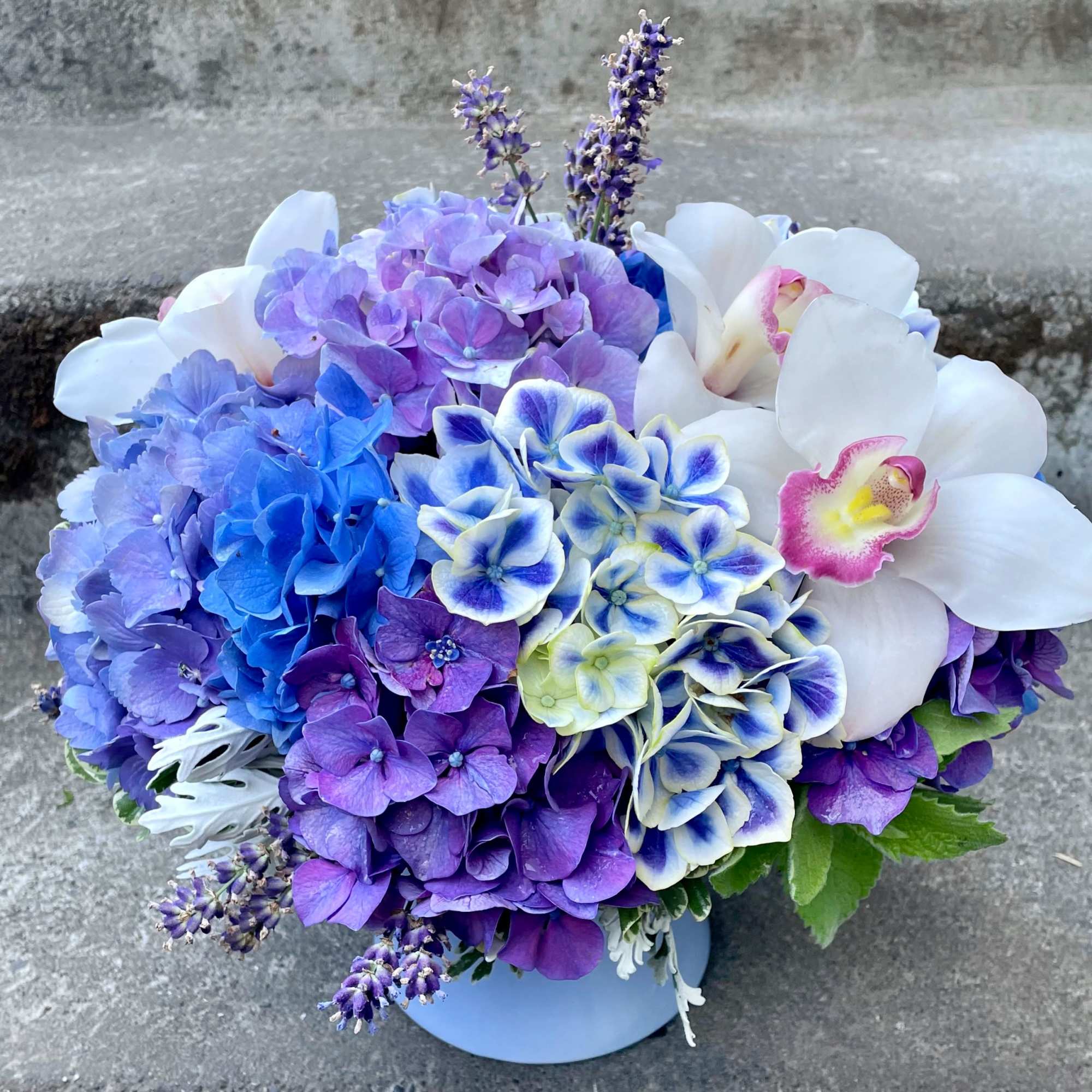 Bouquet of blue, purple, and white flowers in a pale vase