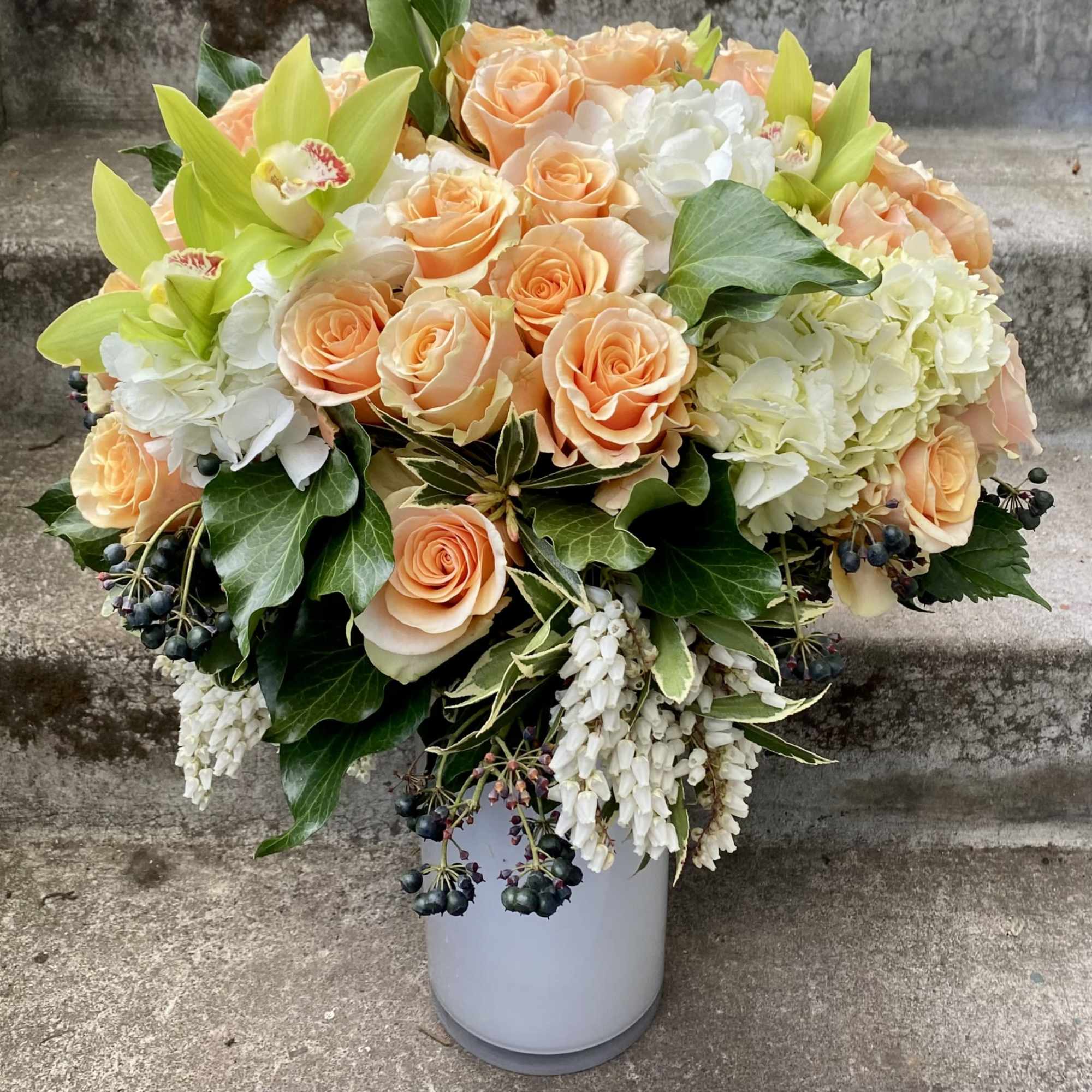 Peach roses and white hydrangeas in a white vase