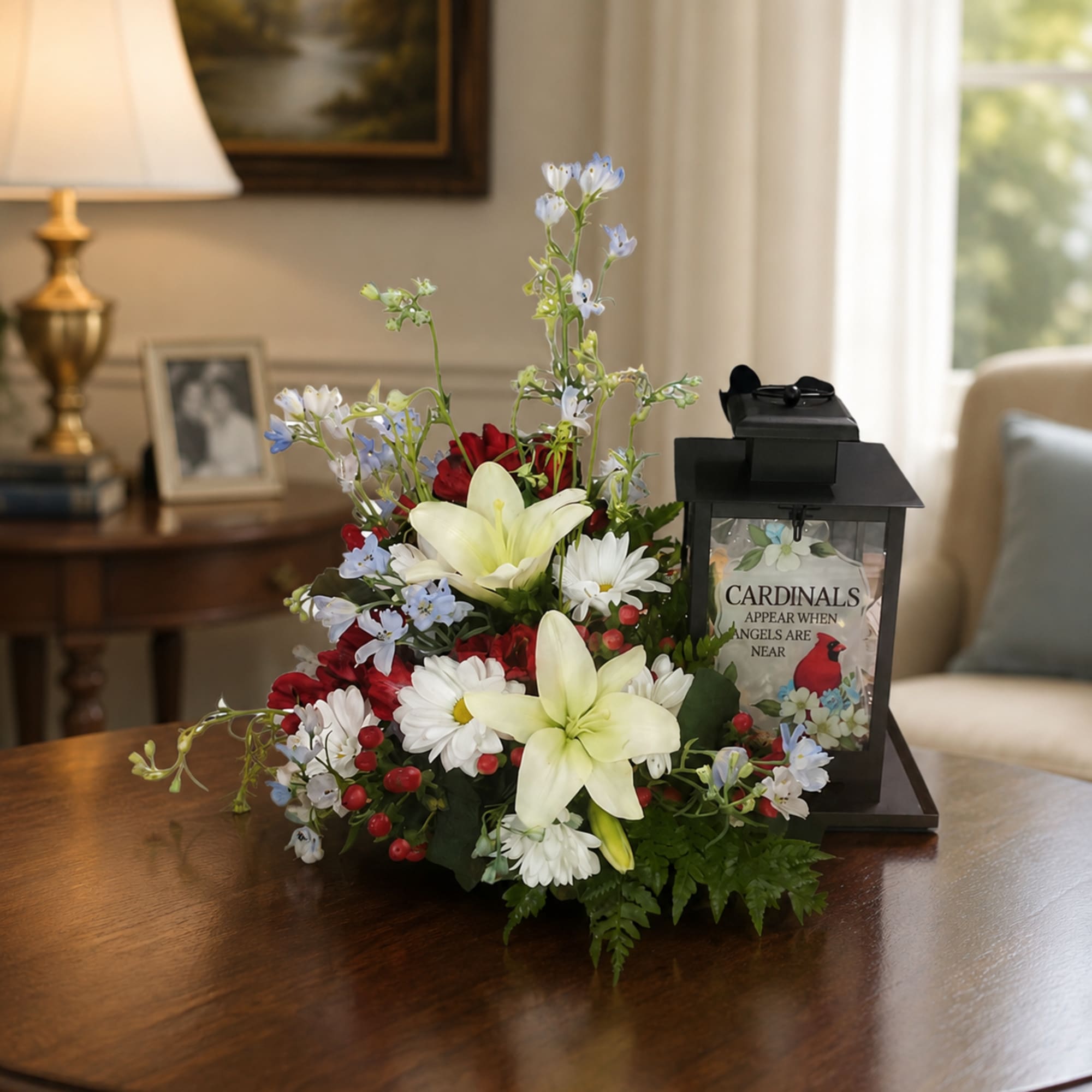 Arrangement of lilies, daisies, and red flowers beside a black memorial lantern