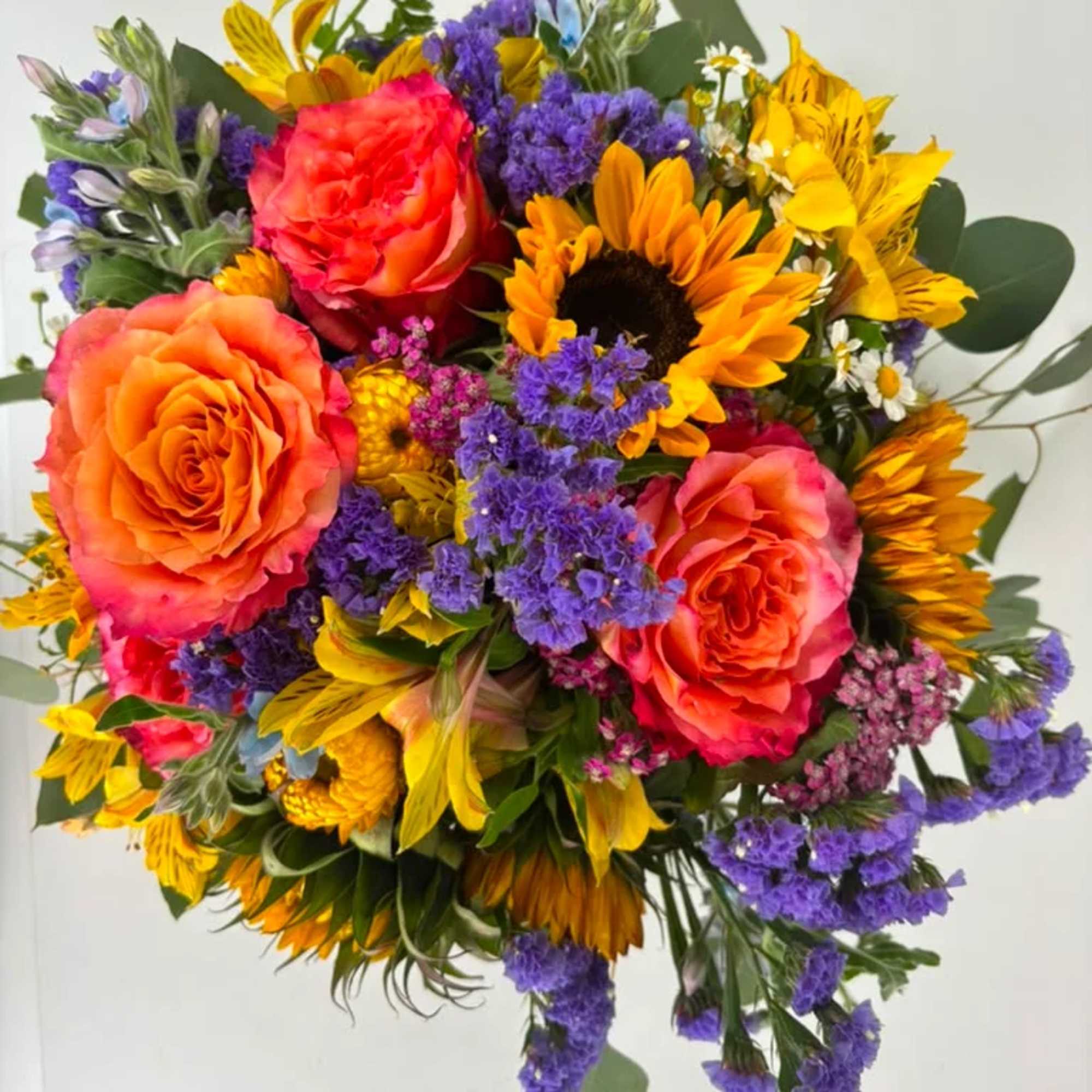 Bouquet of orange roses, sunflowers, and purple filler flowers
