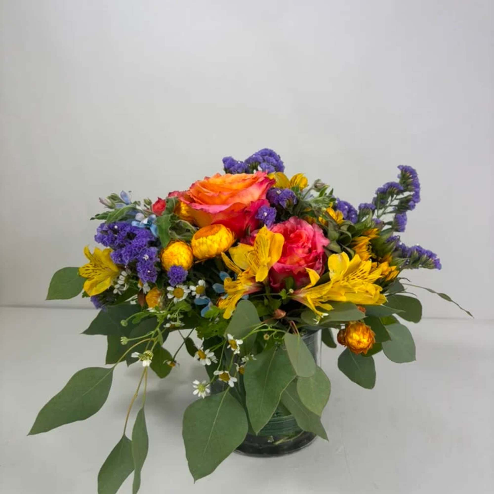 Mixed bouquet of orange, pink, yellow, and purple flowers in a glass vase, photo 2 of 5