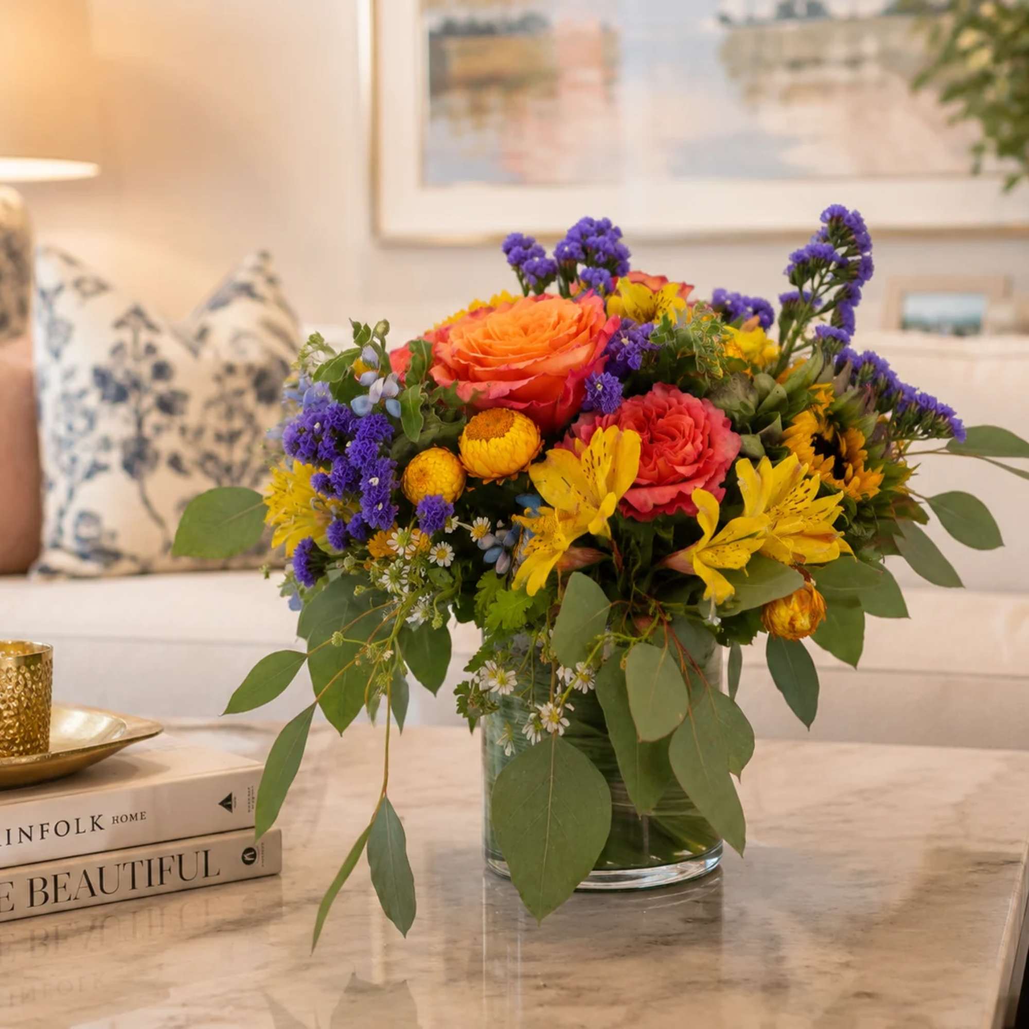 Mixed bouquet of orange, pink, yellow, and purple flowers in a glass vase