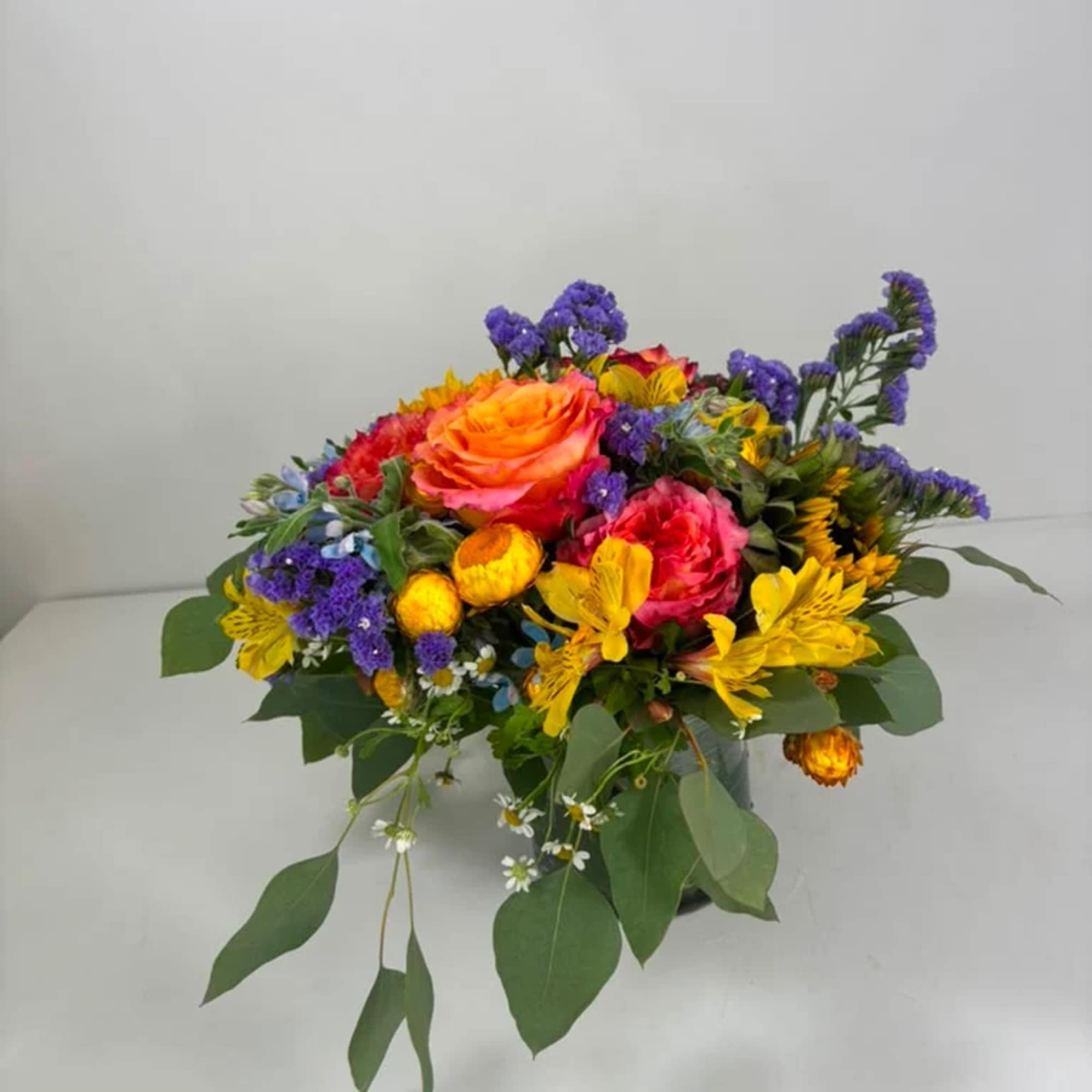 Colorful bouquet with orange and pink roses, yellow blooms, and purple accents