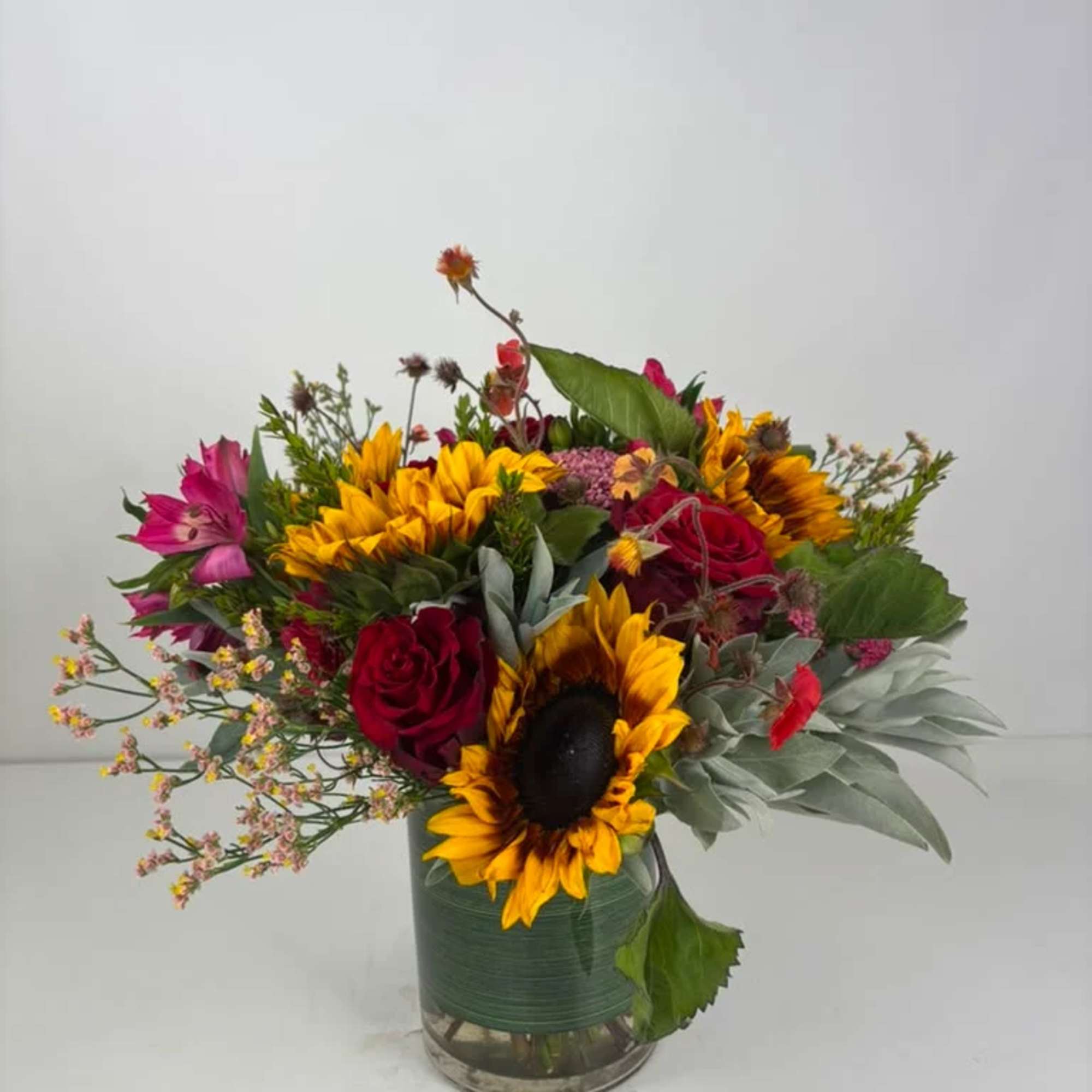 Mixed bouquet with sunflowers and red roses in a glass vase