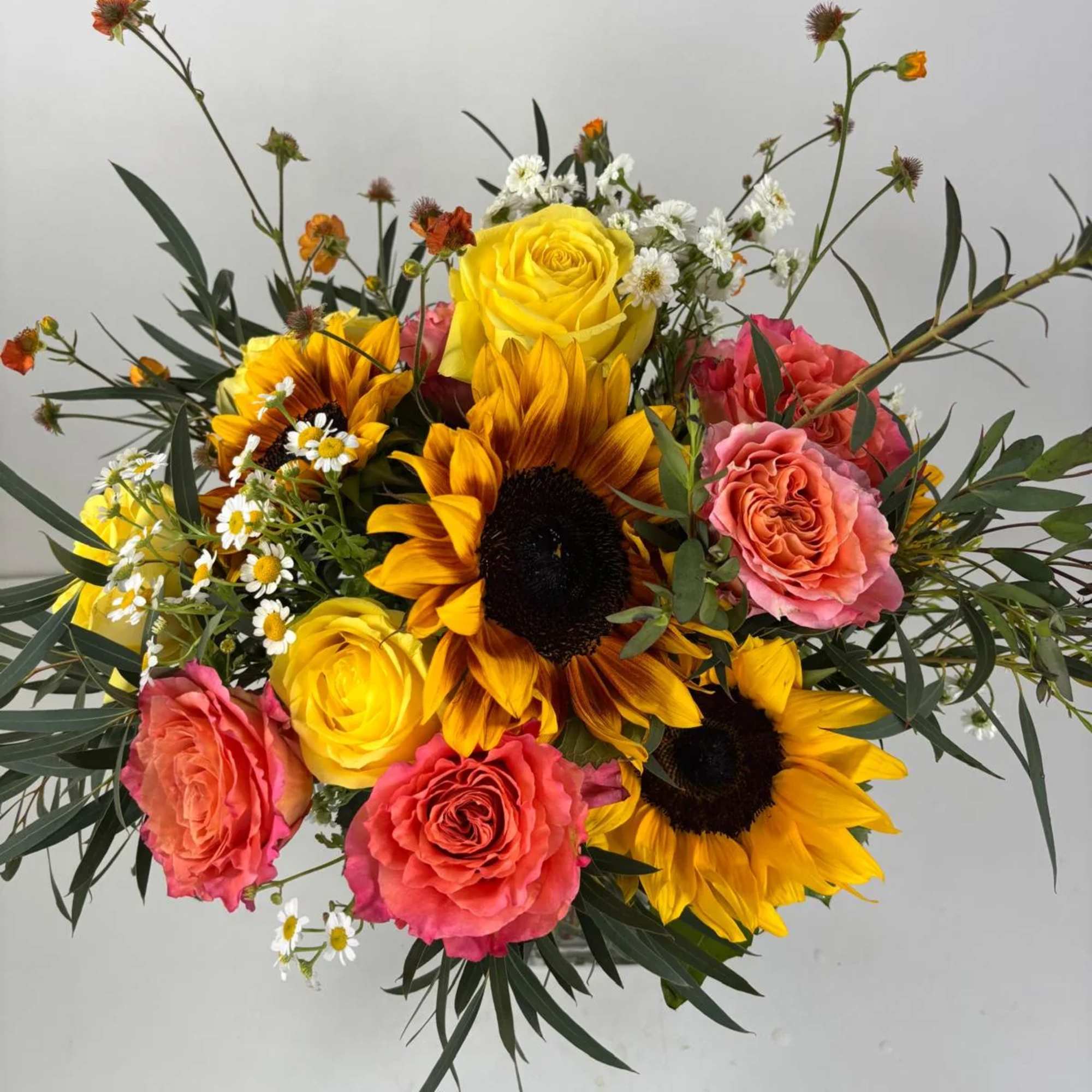 Bouquet of sunflowers, yellow and pink roses, and small white daisies